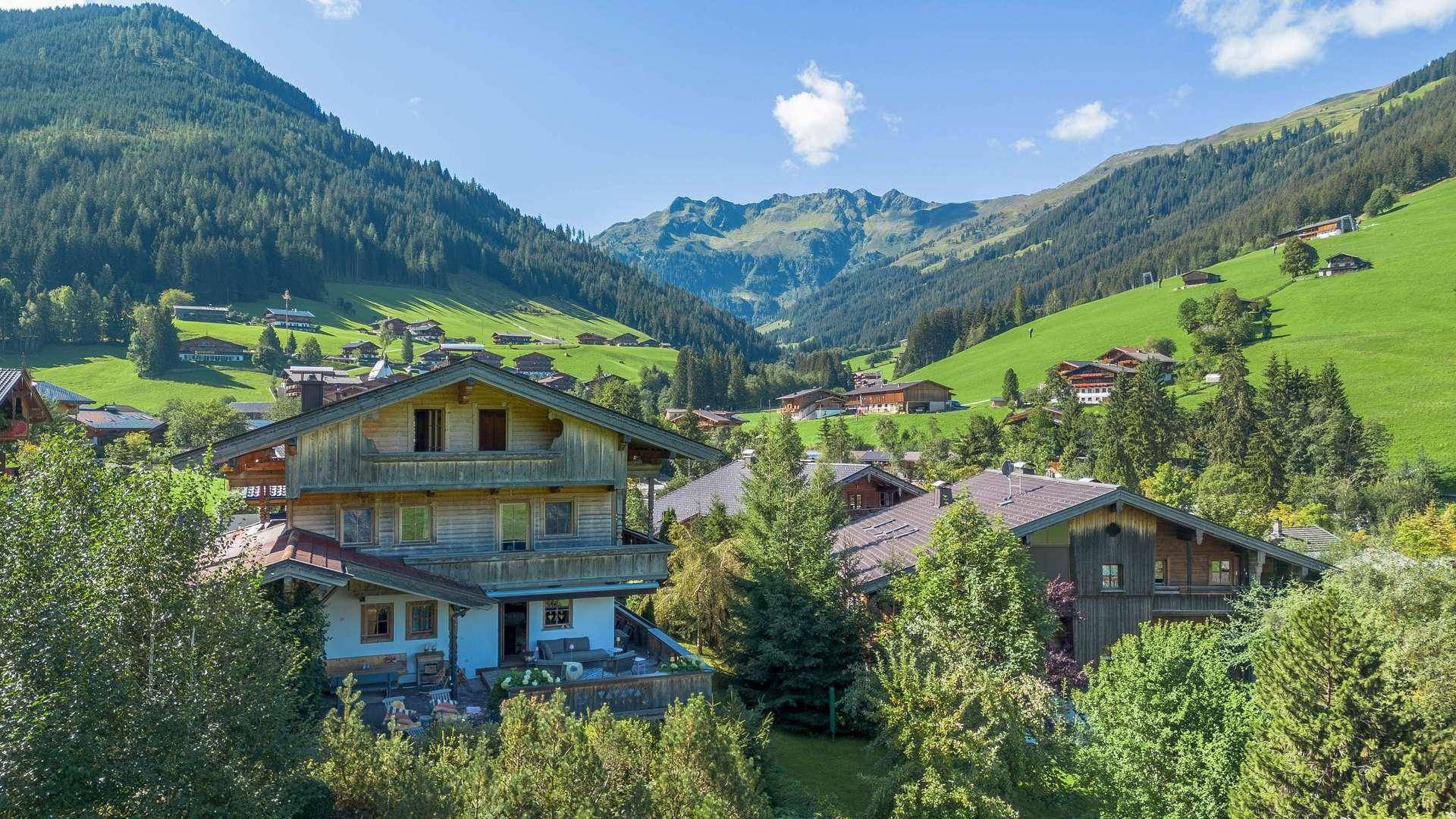 Malerisches Bergdorf in einem weiten Tal, umgeben von grünen Hängen und majestätischen Gipfeln.