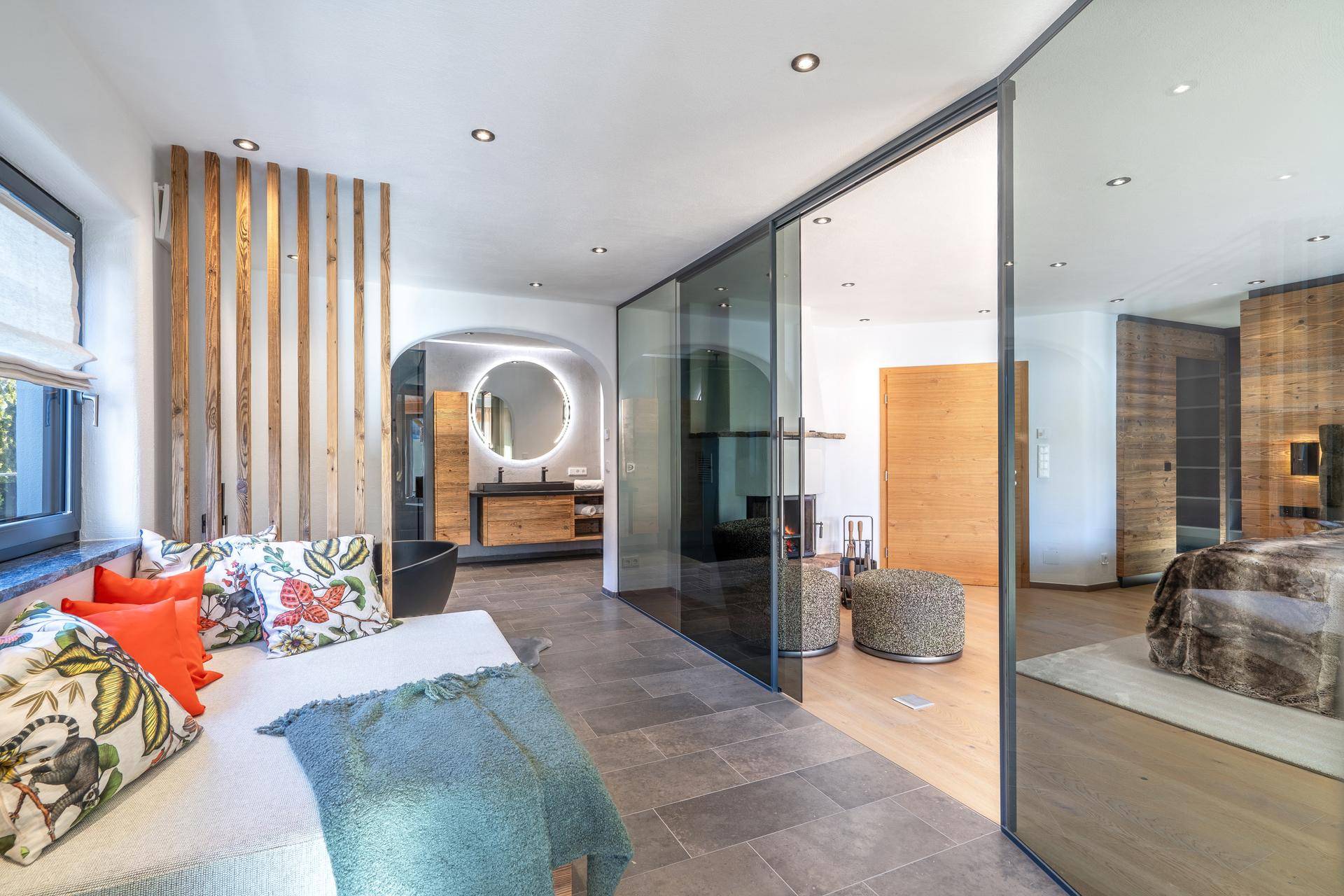 Luxuriöses Badezimmer mit freistehender Badewanne, modernem Waschtisch und Glasabtrennungen zum Schlafbereich.