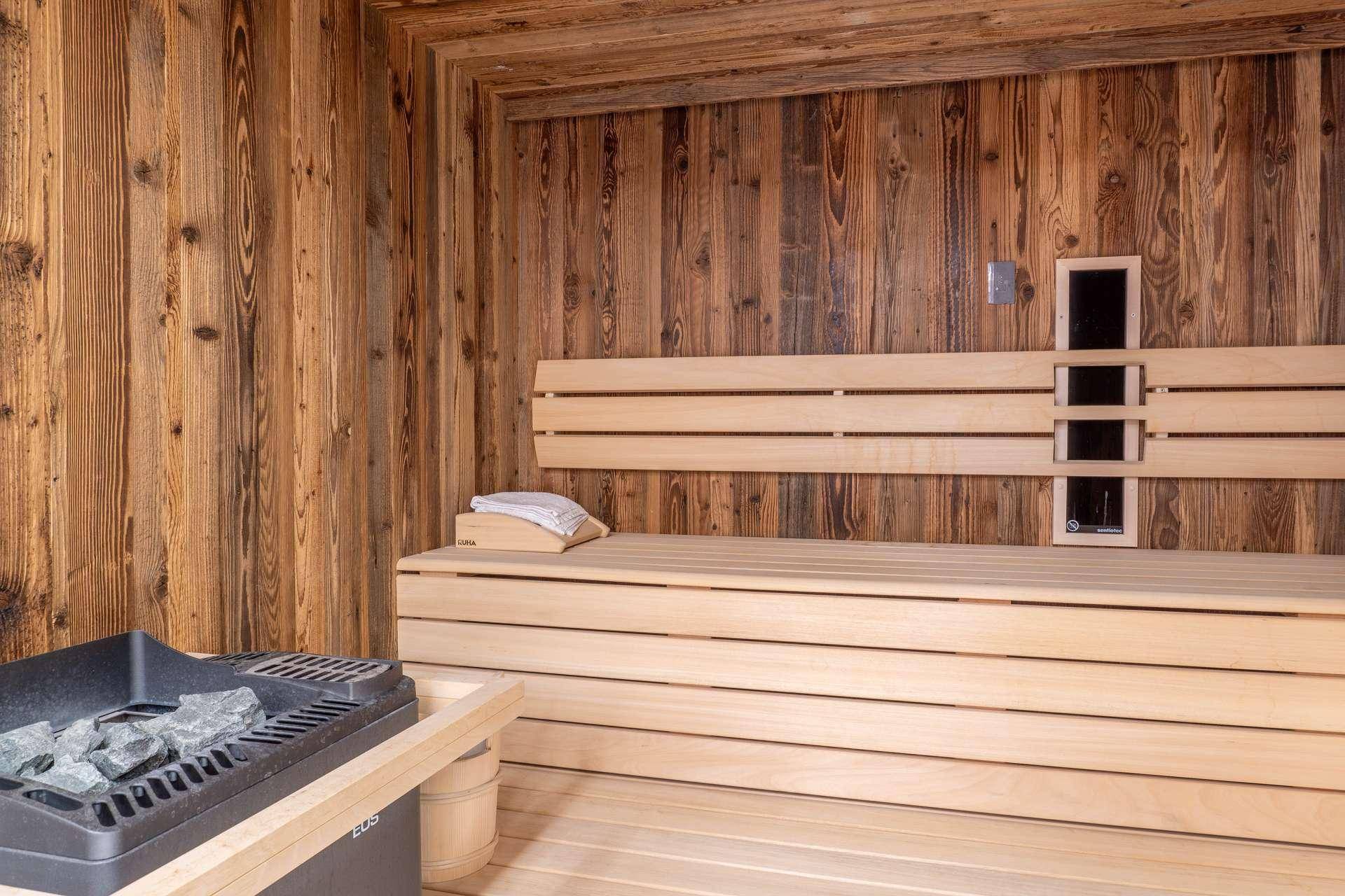 Traditionelle Holzsauna mit bequemen Bänken und einem Saunaofen für Entspannung.