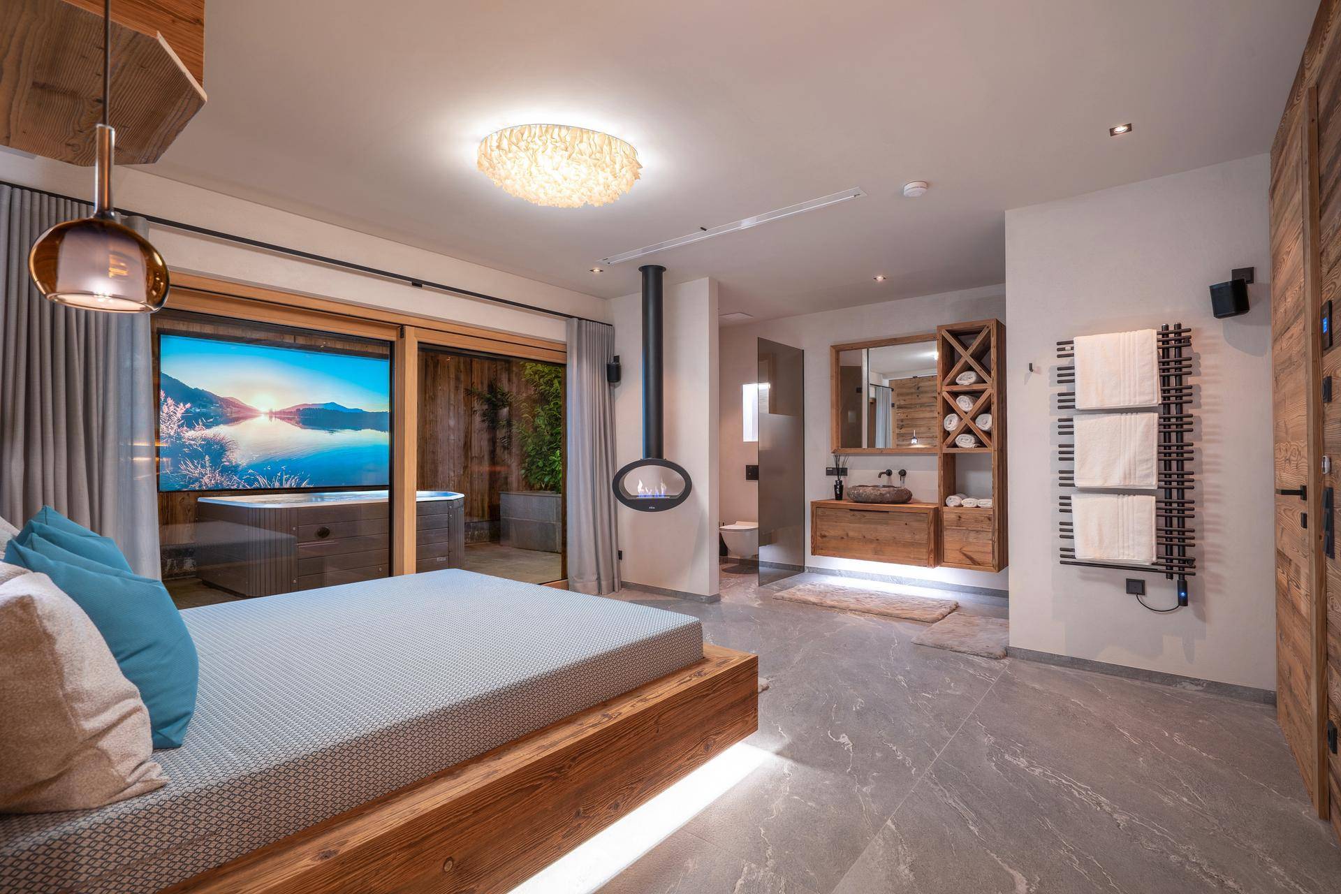 Geräumiges Schlafzimmer mit integriertem Badbereich, Kamin und Zugang zu einem Whirlpool im Freien.