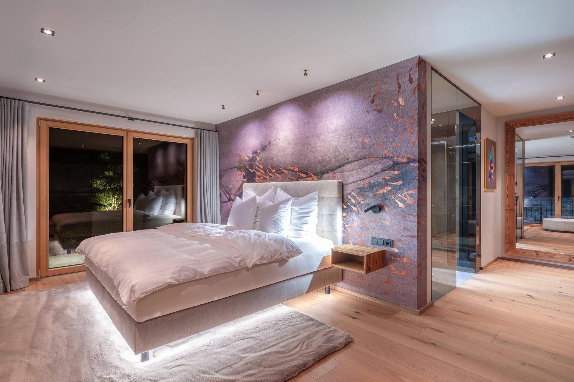 Modernes Schlafzimmer mit Holzboden, indirekter Beleuchtung und Zugang zur Terrasse.