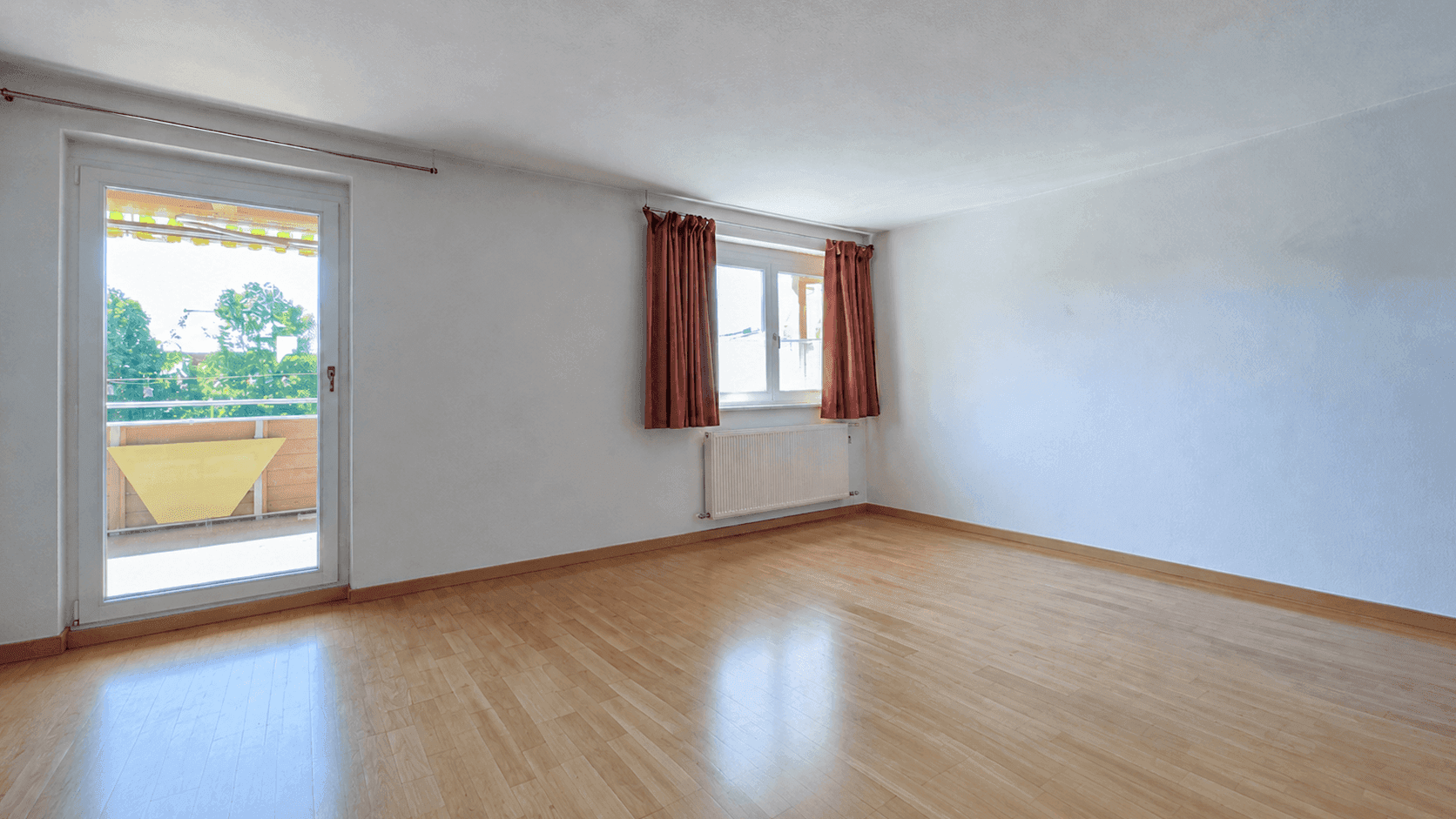 Heller Wohnraum mit Parkettboden und direktem Zugang zu einem sonnigen Balkon.