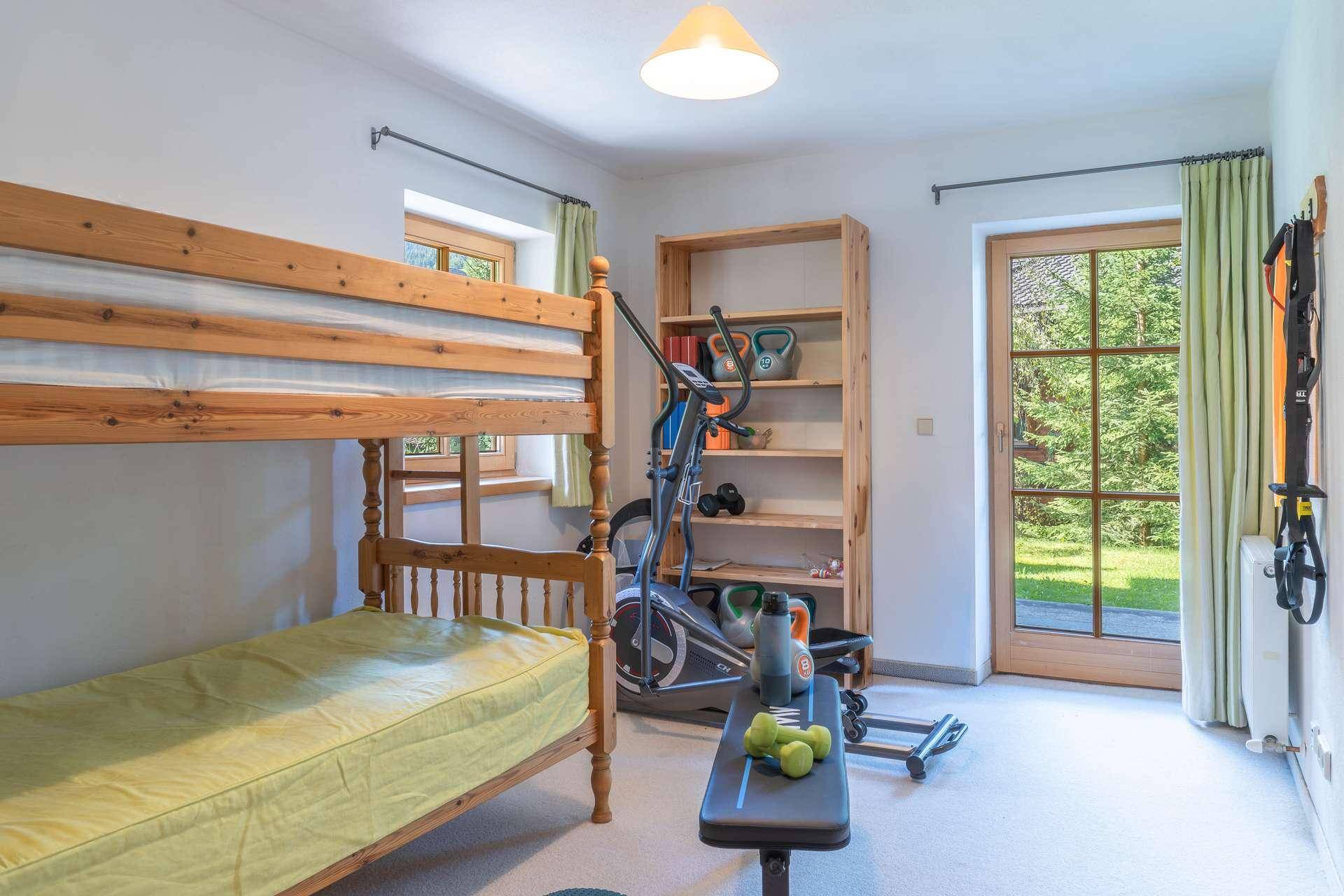 Geräumiges Zimmer mit Etagenbett und Fitnessgeräten, ideal als Gäste- oder Sportzimmer.