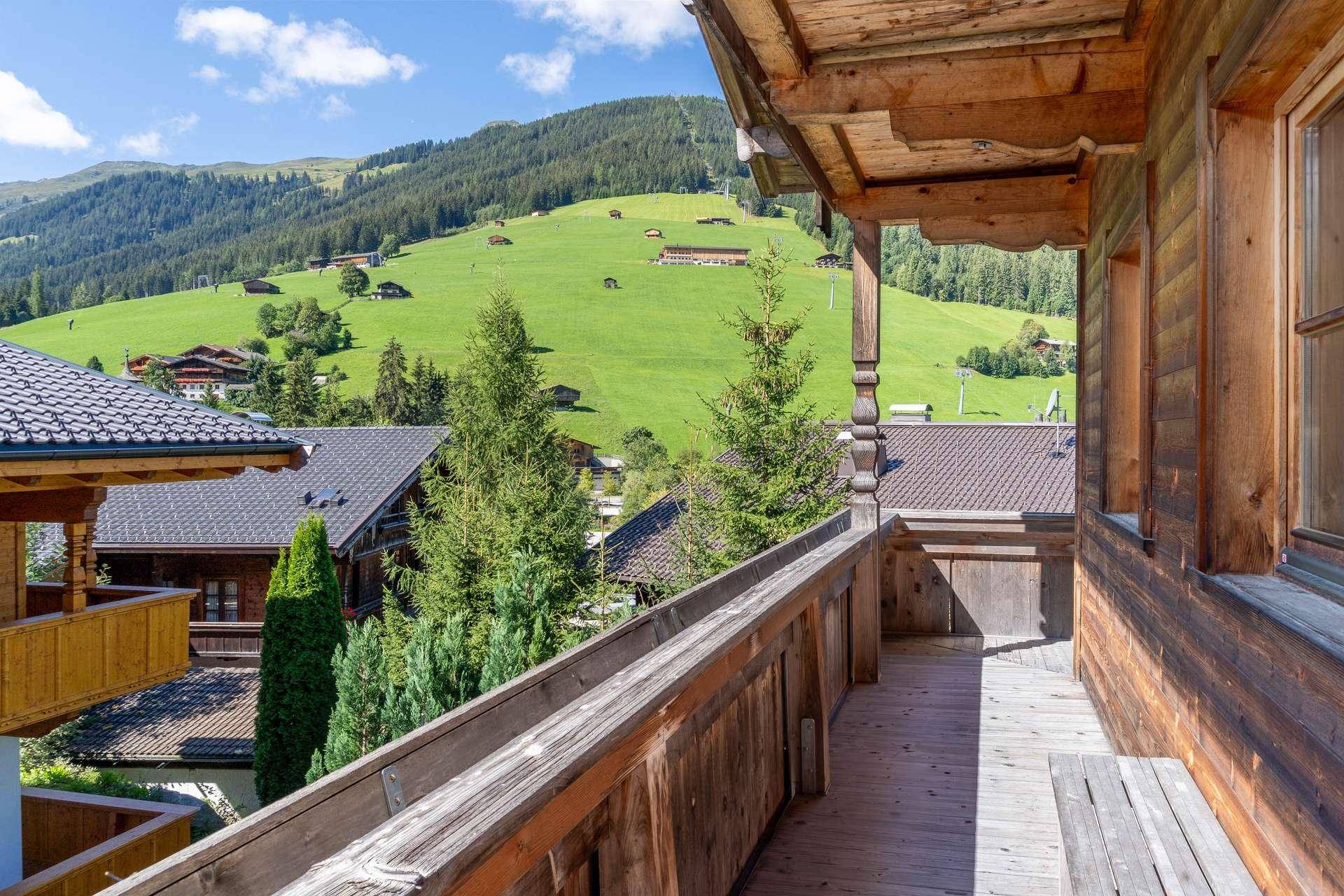 Langer Holzbalkon mit rustikalem Charme und weitem Blick über die grünen Berghänge.