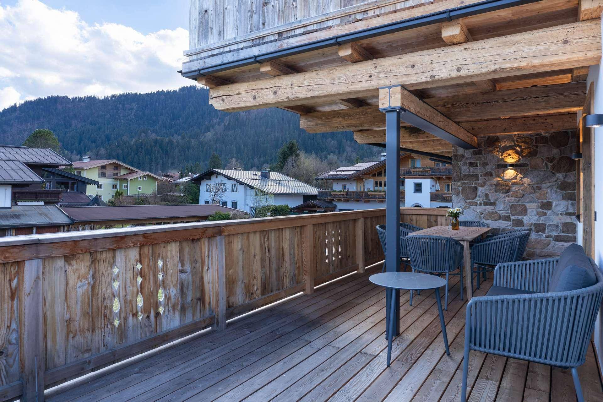 Möblierter Holzbalkon mit Sitzgelegenheiten und Blick auf die umliegende Berglandschaft.