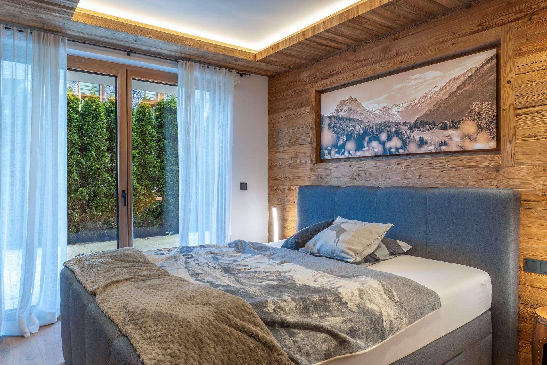 Schlafzimmer mit Holzwänden, großem Bett und direktem Zugang zu einem Außenbereich.
