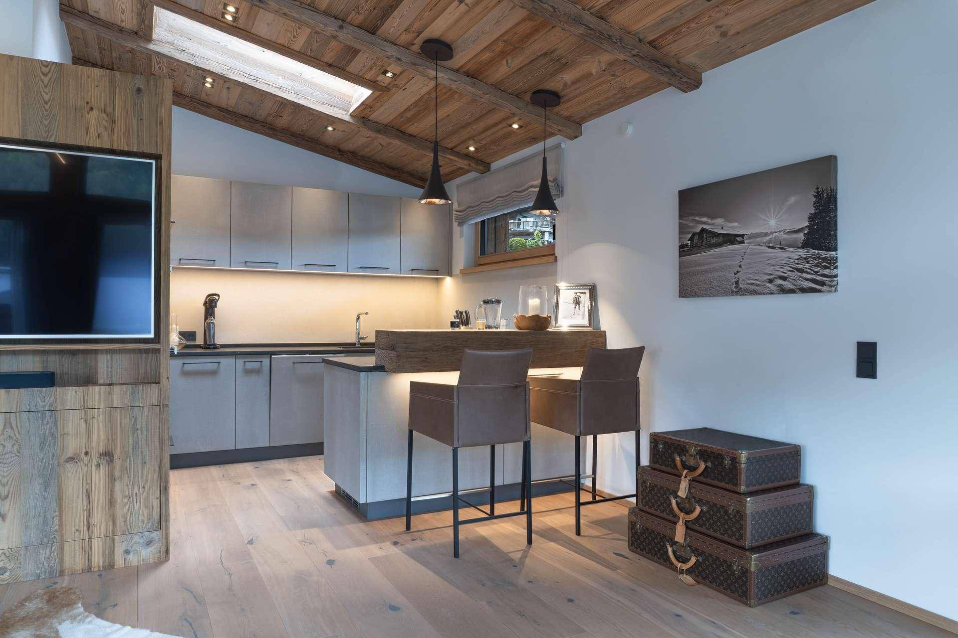 Moderne Küchenzeile mit Frühstücksbar, Holzbalkendecke und integrierten Geräten.