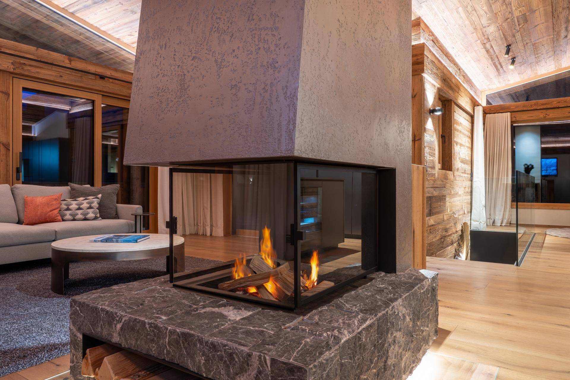 Moderner, freistehender Kamin als zentrales Element im stilvollen Wohnbereich mit Holzboden.