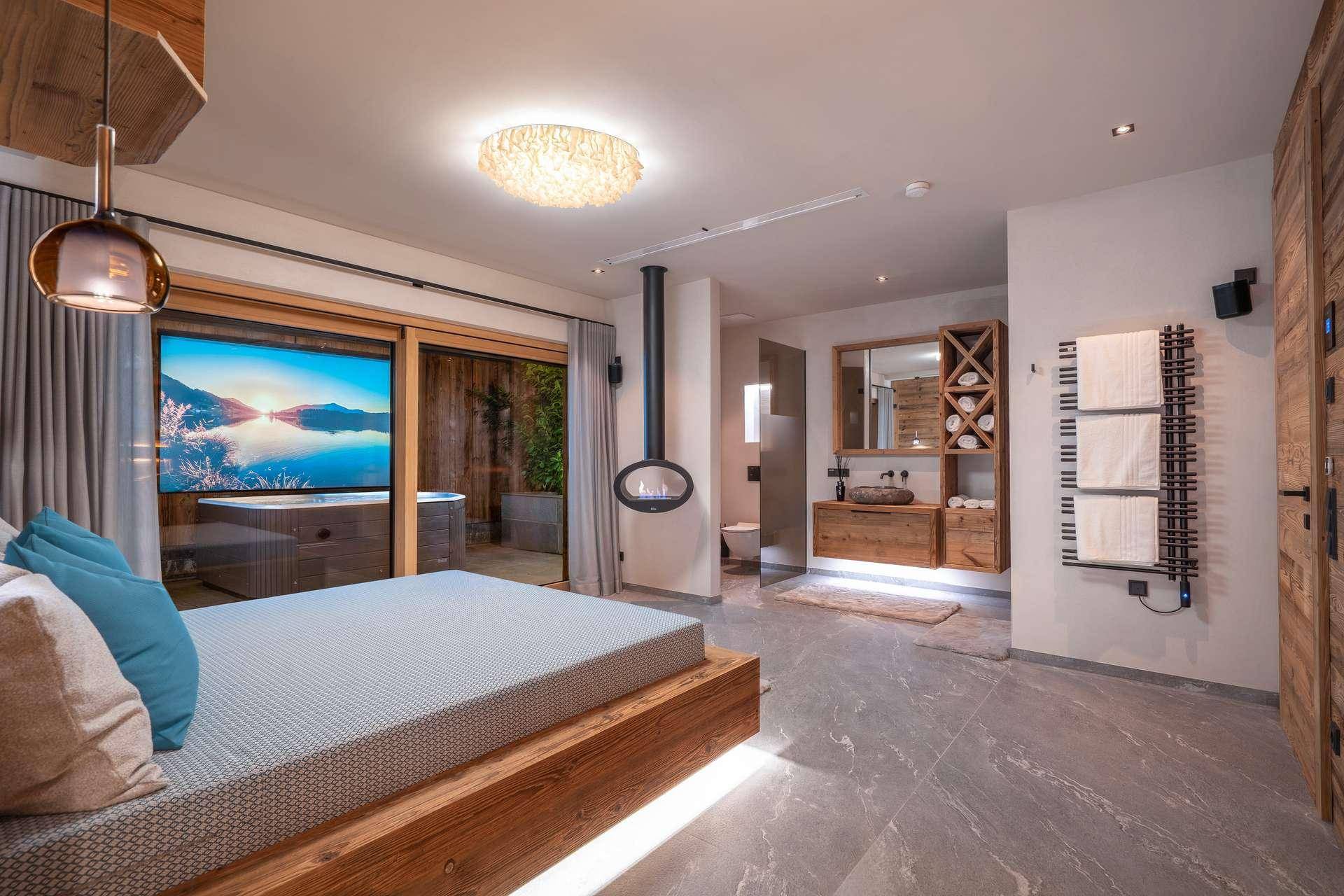 Geräumiges Schlafzimmer mit Kamin, freistehendem Waschbecken und Zugang zu einem Außenbereich.