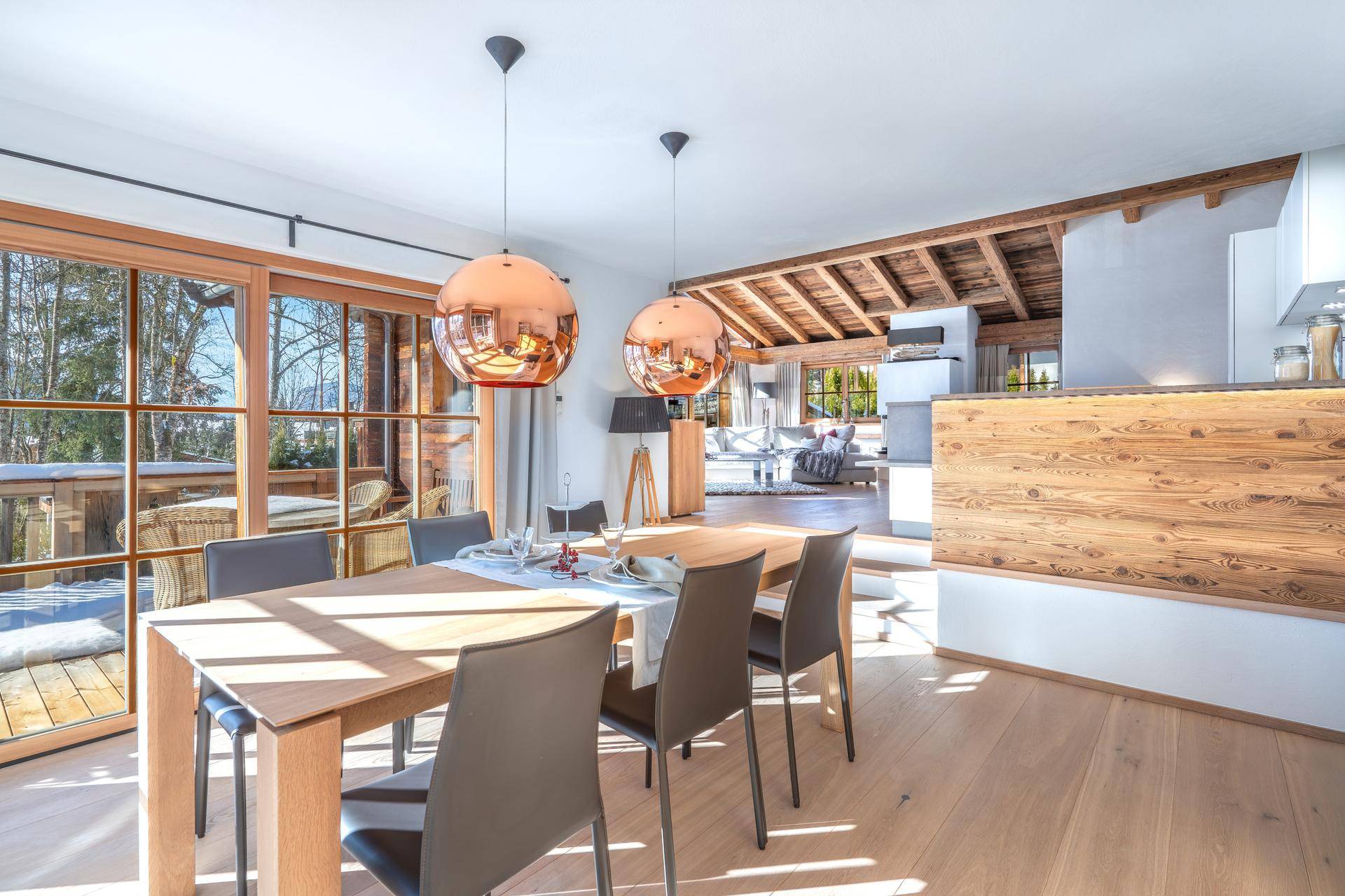 Heller Essbereich mit Holztisch, modernen Pendelleuchten und Zugang zum Balkon.