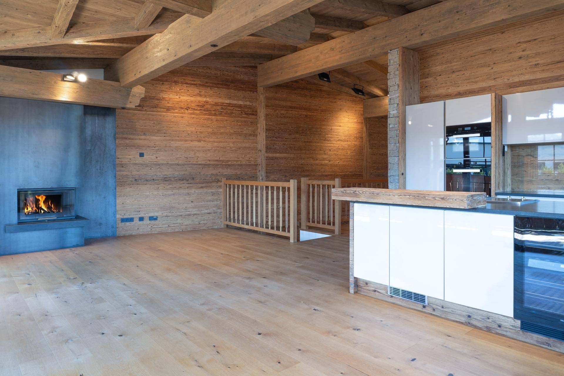 Gemütlicher Wohnbereich mit Kamin, Holzwänden und offener Küche mit modernen Geräten.