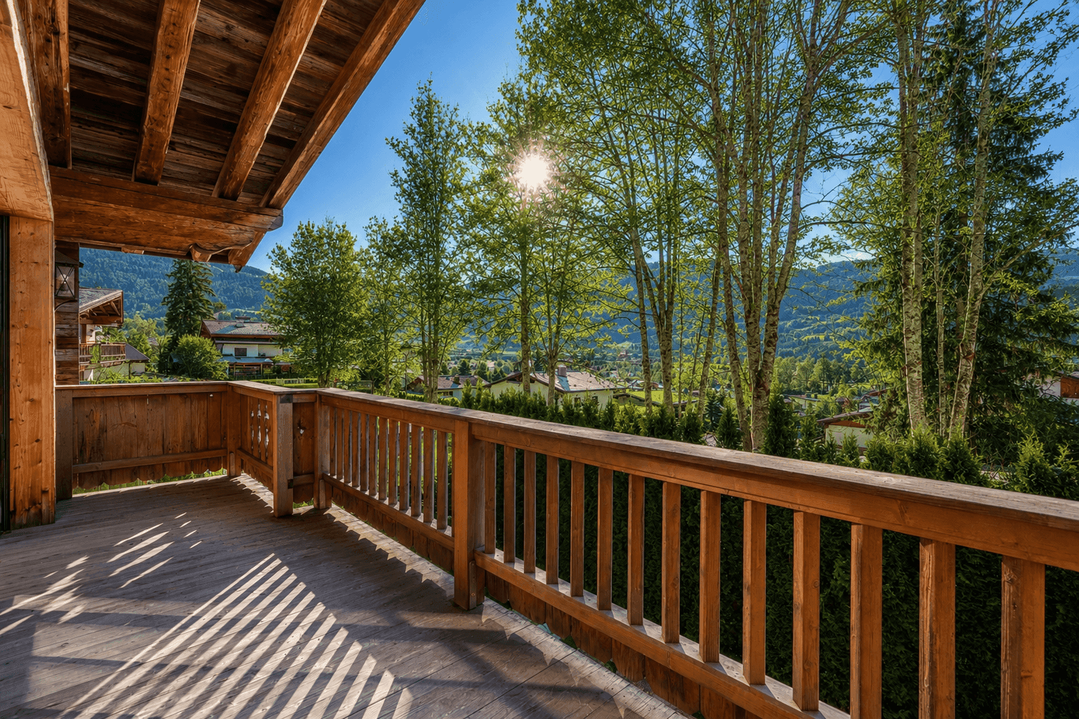 Geräumiger Holzbalkon mit Geländer und weitem Blick auf die grüne Landschaft.