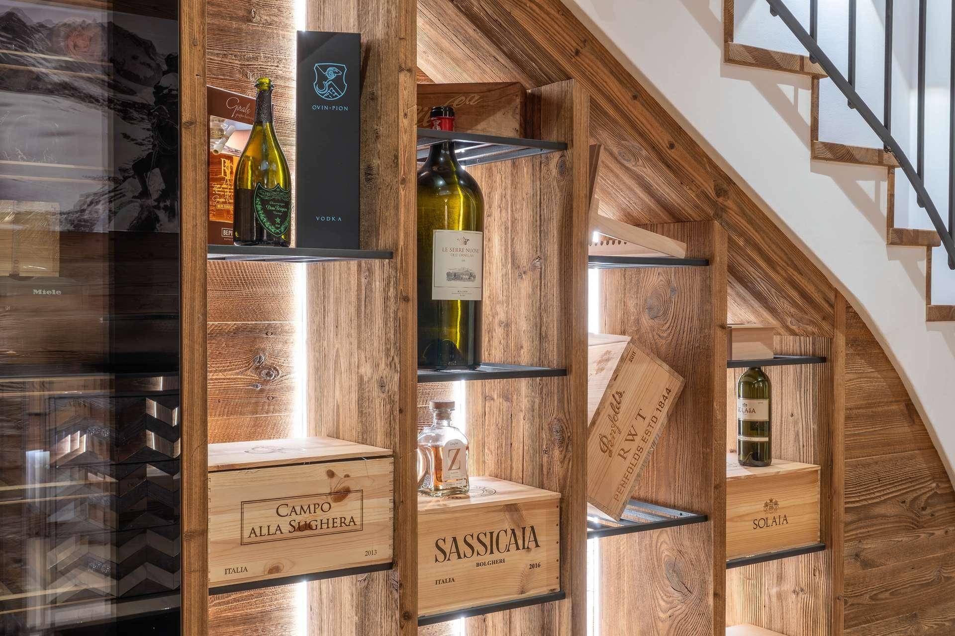 Stilvoller Weinkeller unter der Treppe mit Holzregalen und einer Auswahl an Weinen.