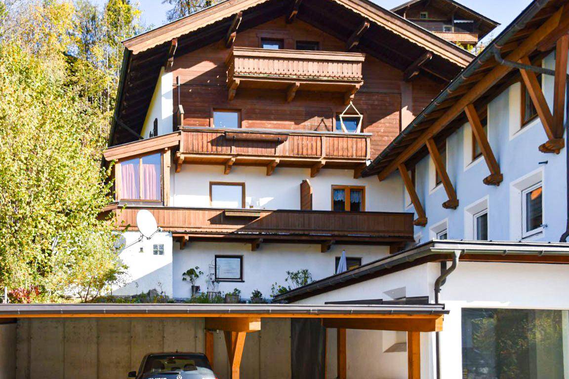 Detailansicht der Fassade mit Holzbalkonen und traditionellen Elementen, umgeben von grüner Natur.
