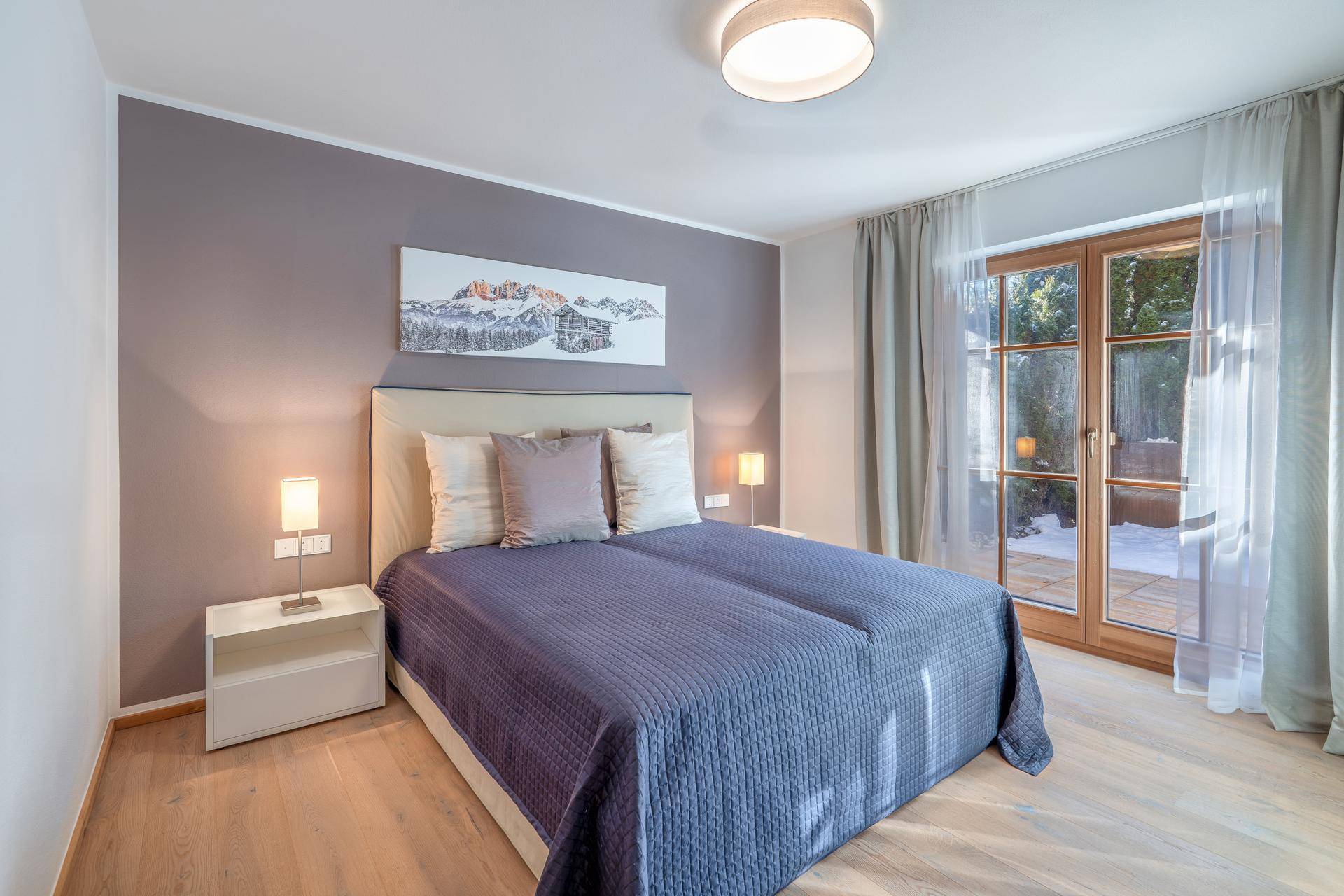Gemütliches Schlafzimmer mit Doppelbett, Holzboden und Zugang zu einer Terrasse oder Balkon.