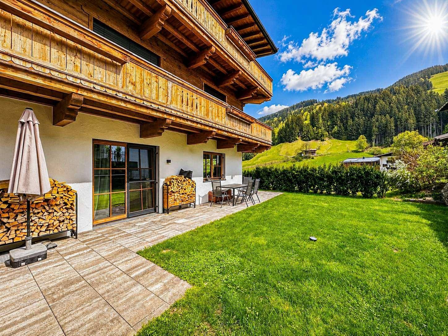 Traditionelles Gebäude mit großem Garten, Terrasse und Bergblick in alpiner Umgebung.