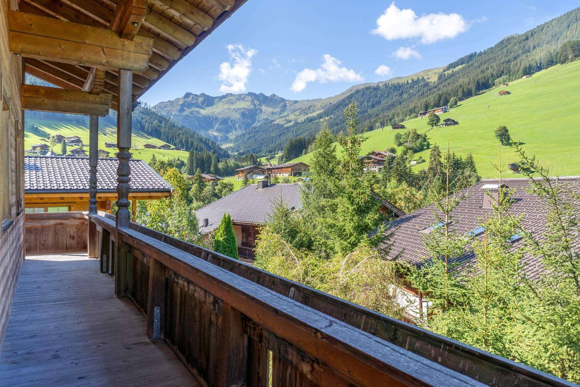 Traditioneller Holzbalkon mit Geländer und atemberaubendem Panoramablick auf die umliegenden Berge.