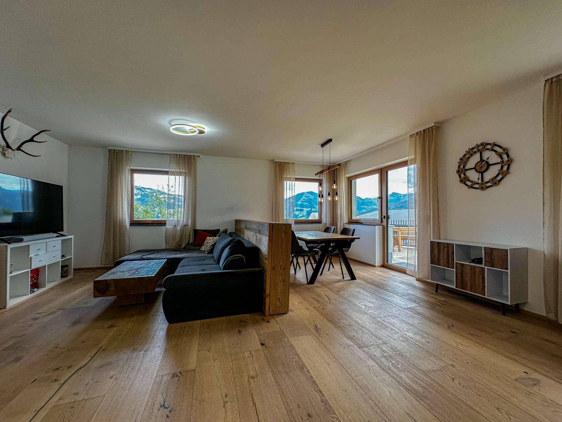 Geräumiger Wohn-Essbereich mit Holzboden, bequemer Couch und Esstisch mit Bergblick.