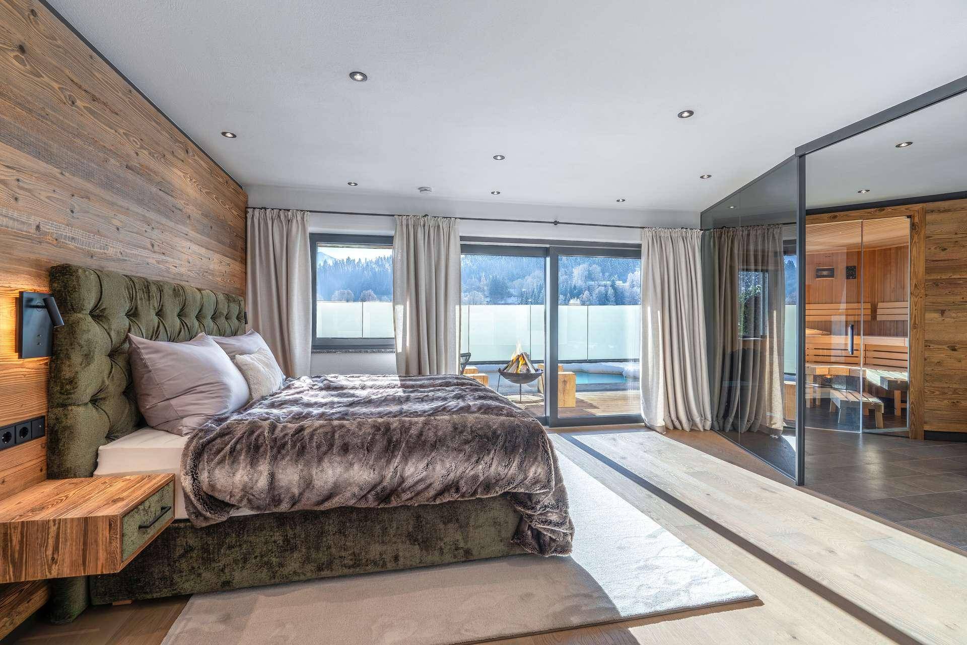 Luxuriöses Schlafzimmer mit Holzwänden, großem Bett, Balkonzugang und integrierter Sauna.