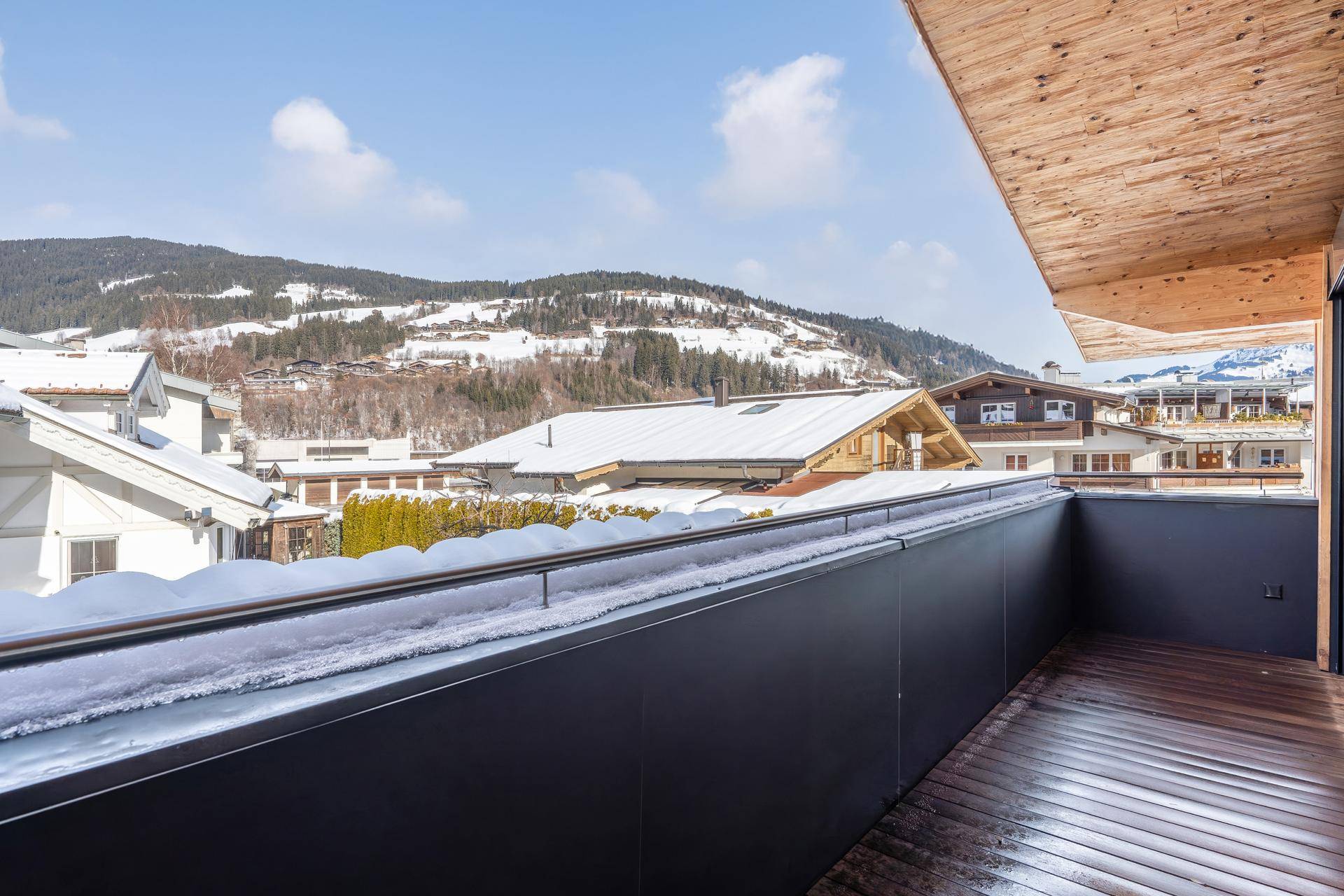 Geräumiger Balkon mit Holzboden und weitem Blick auf die verschneite Berglandschaft.
