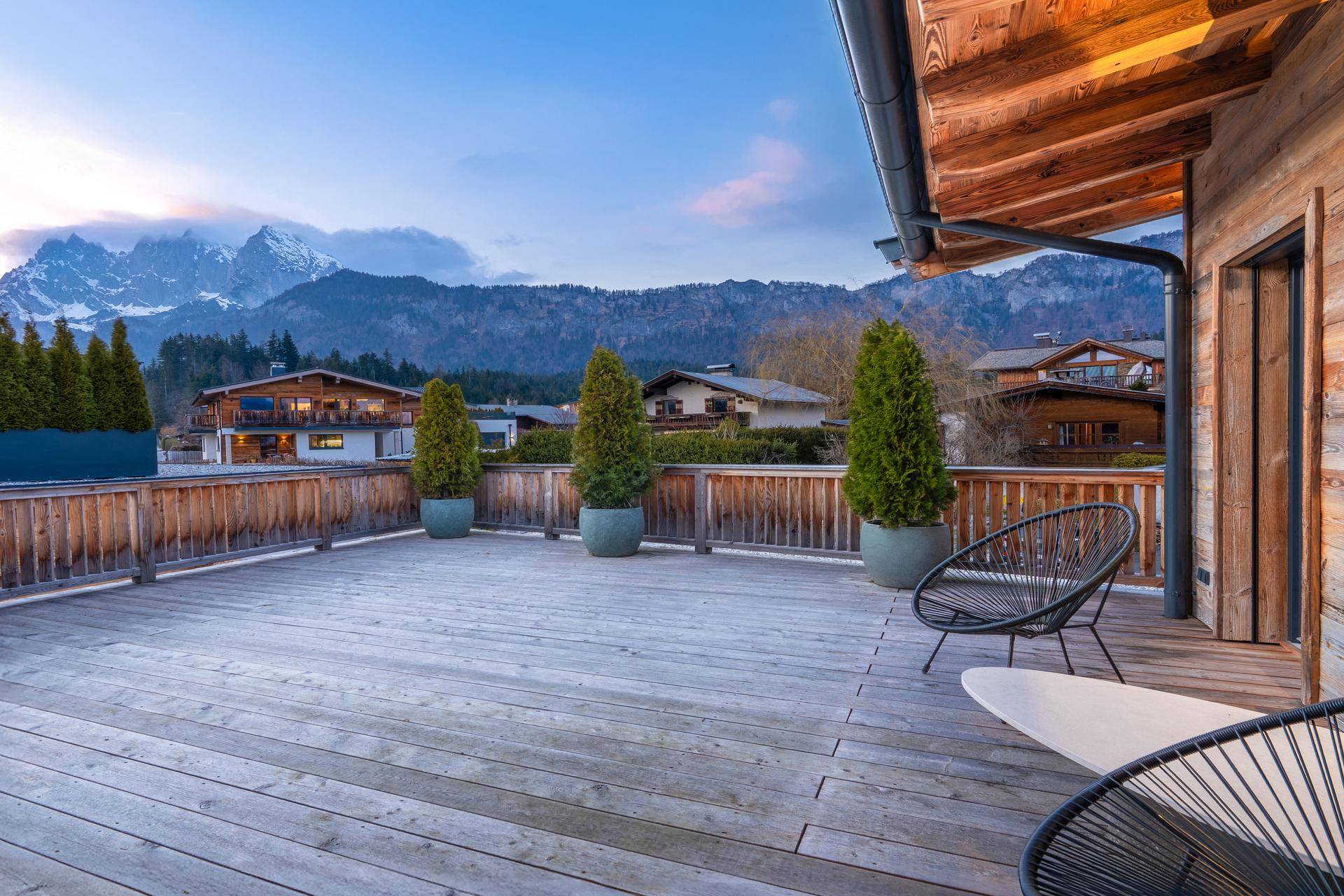 Große Holzterrasse mit Sitzgelegenheiten und Blick auf die umliegende Berglandschaft.