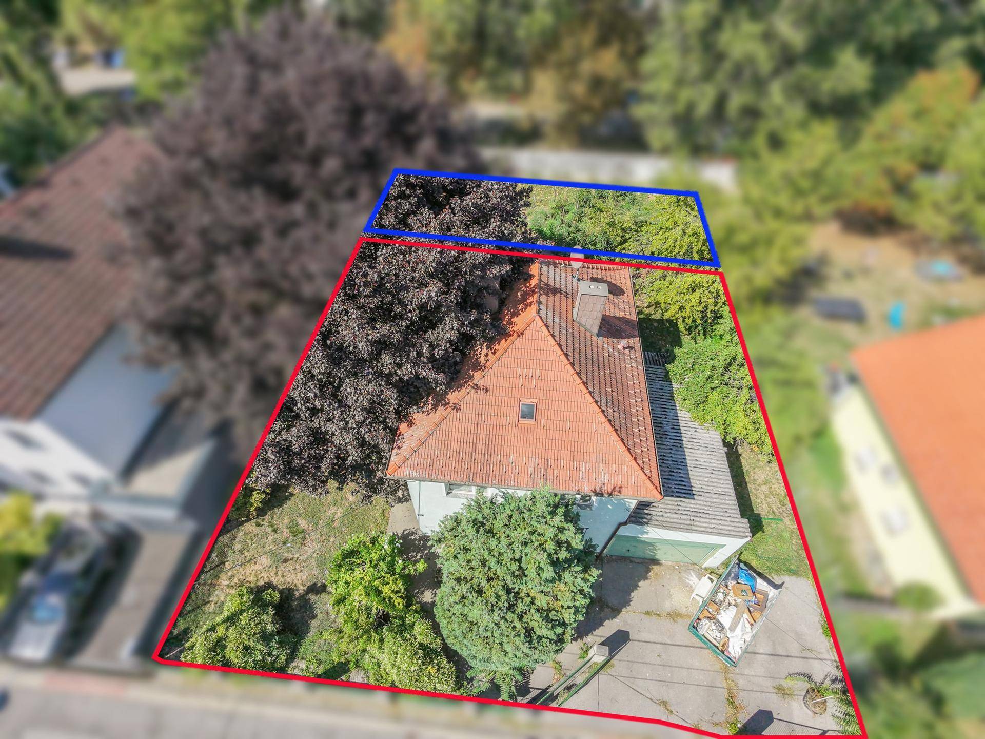 Luftaufnahme eines Einfamilienhauses mit angrenzendem Grundstück und umliegender Natur.