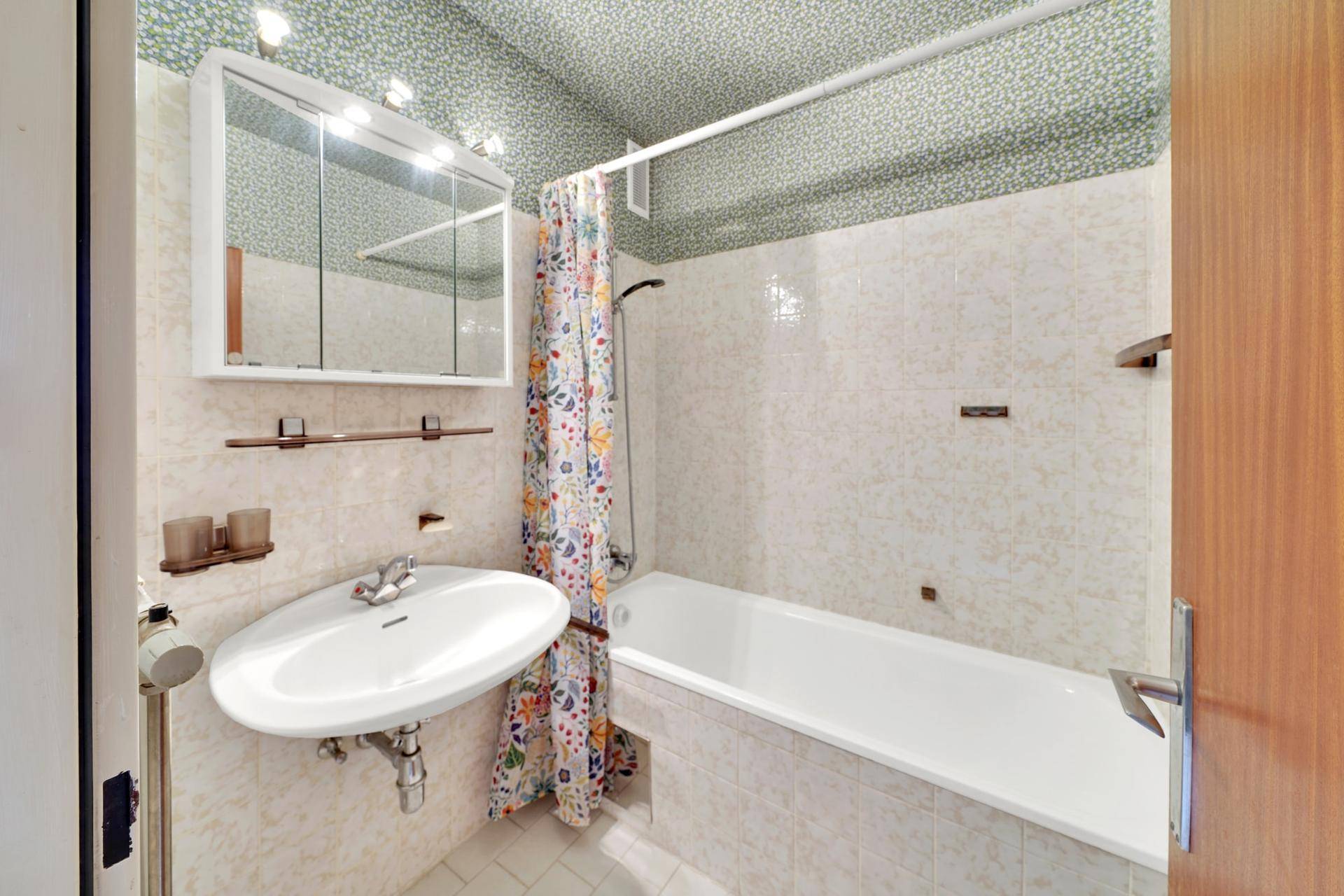 Badezimmer mit Badewanne, Waschbecken und gemusterter Duschvorhang.