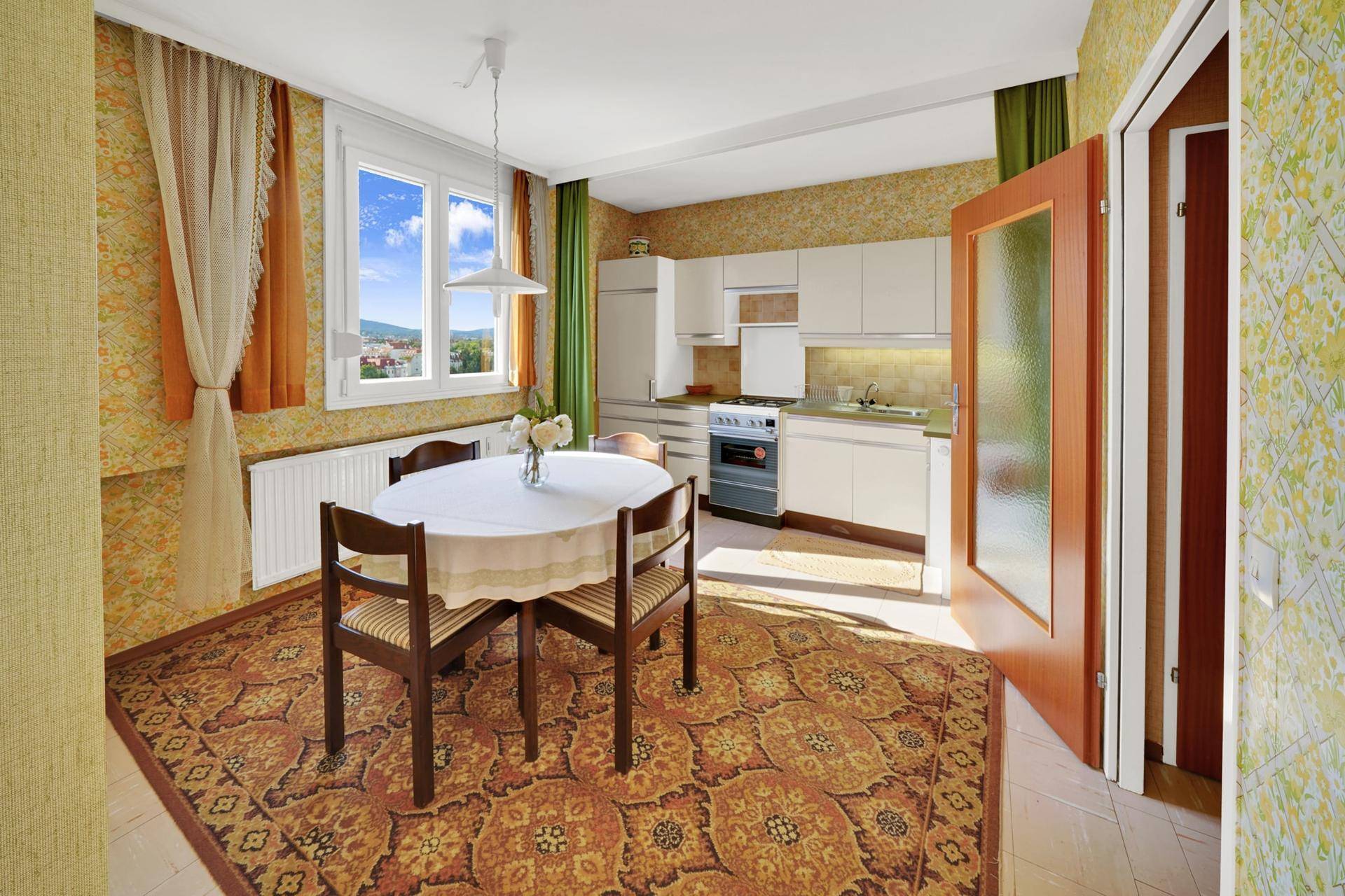 Geräumige Wohnküche mit Esstisch, Einbauküche und Fenster mit Grünblick.