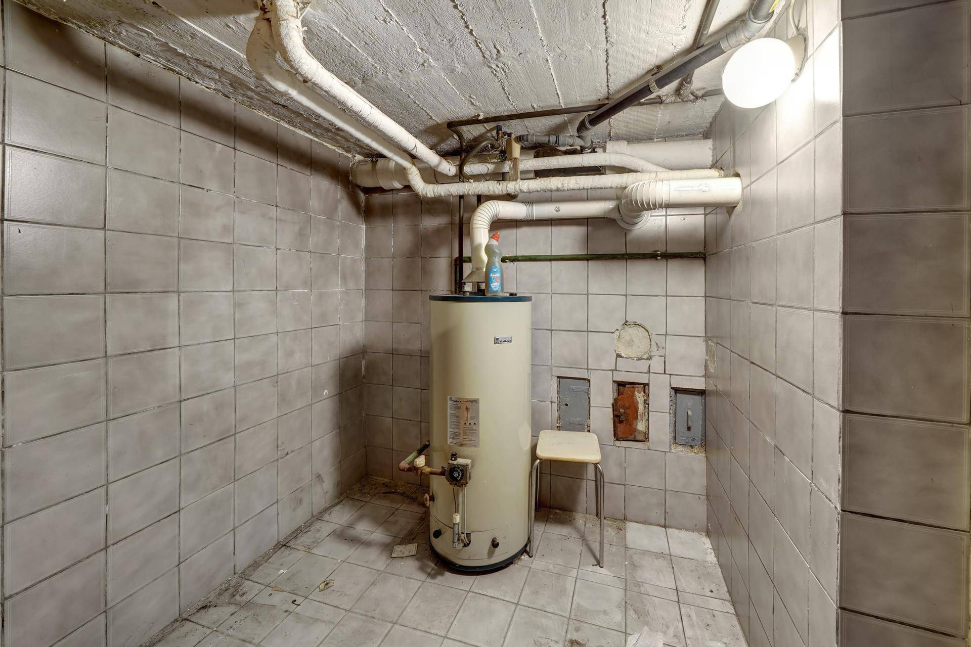 Kellerraum mit Warmwasserboiler und gefliesten Wänden, als Technikraum nutzbar.