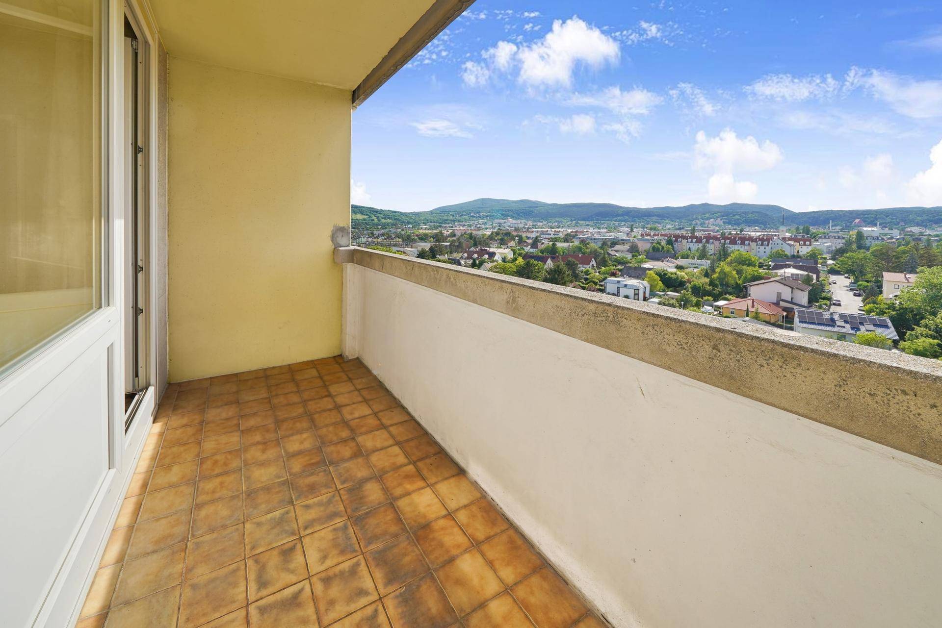 Geräumiger Balkon mit Fliesenboden und weitem Blick über die Stadt und Berge.