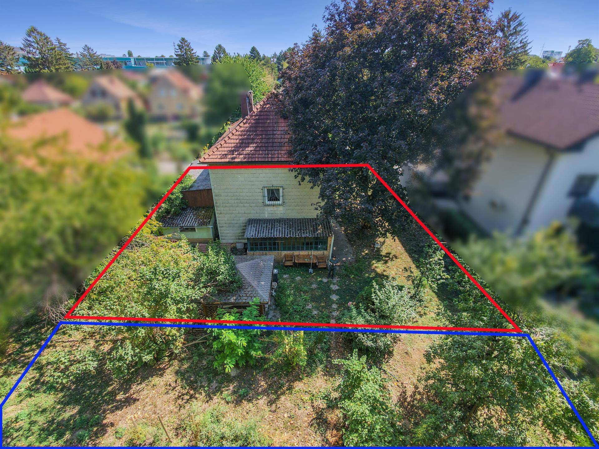 Luftaufnahme des hinteren Bereichs eines Einfamilienhauses mit Garten und Grundstück.