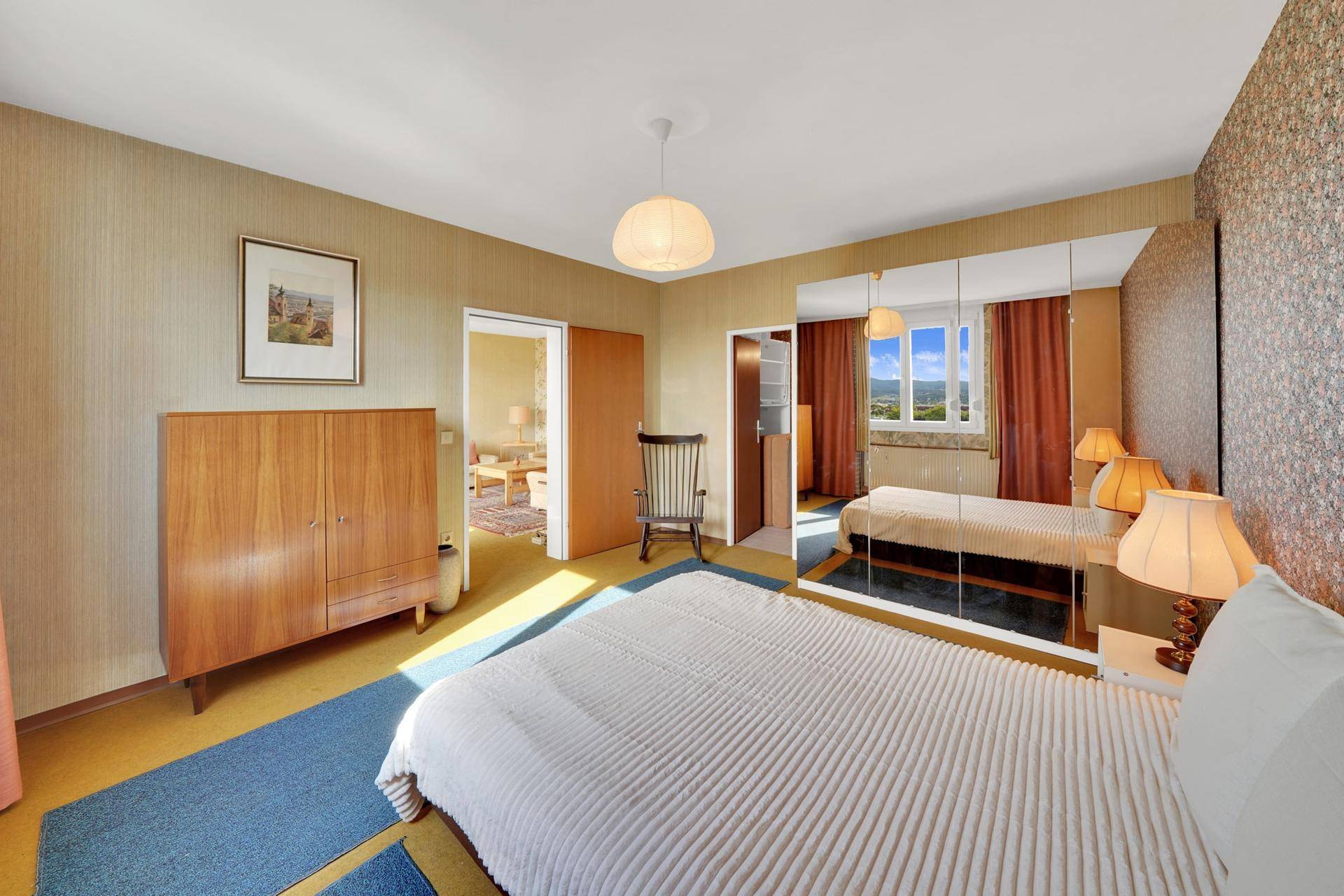 Helles Schlafzimmer mit Kleiderschrank und Zugang zu einem weiteren Raum.