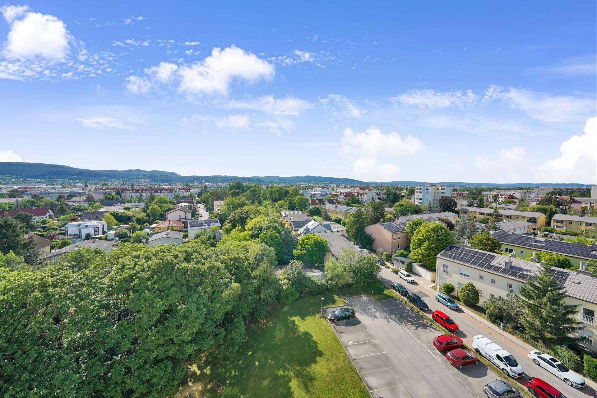 Panoramablick über die Wohnsiedlung mit Straßen, geparkten Autos und viel Grün.