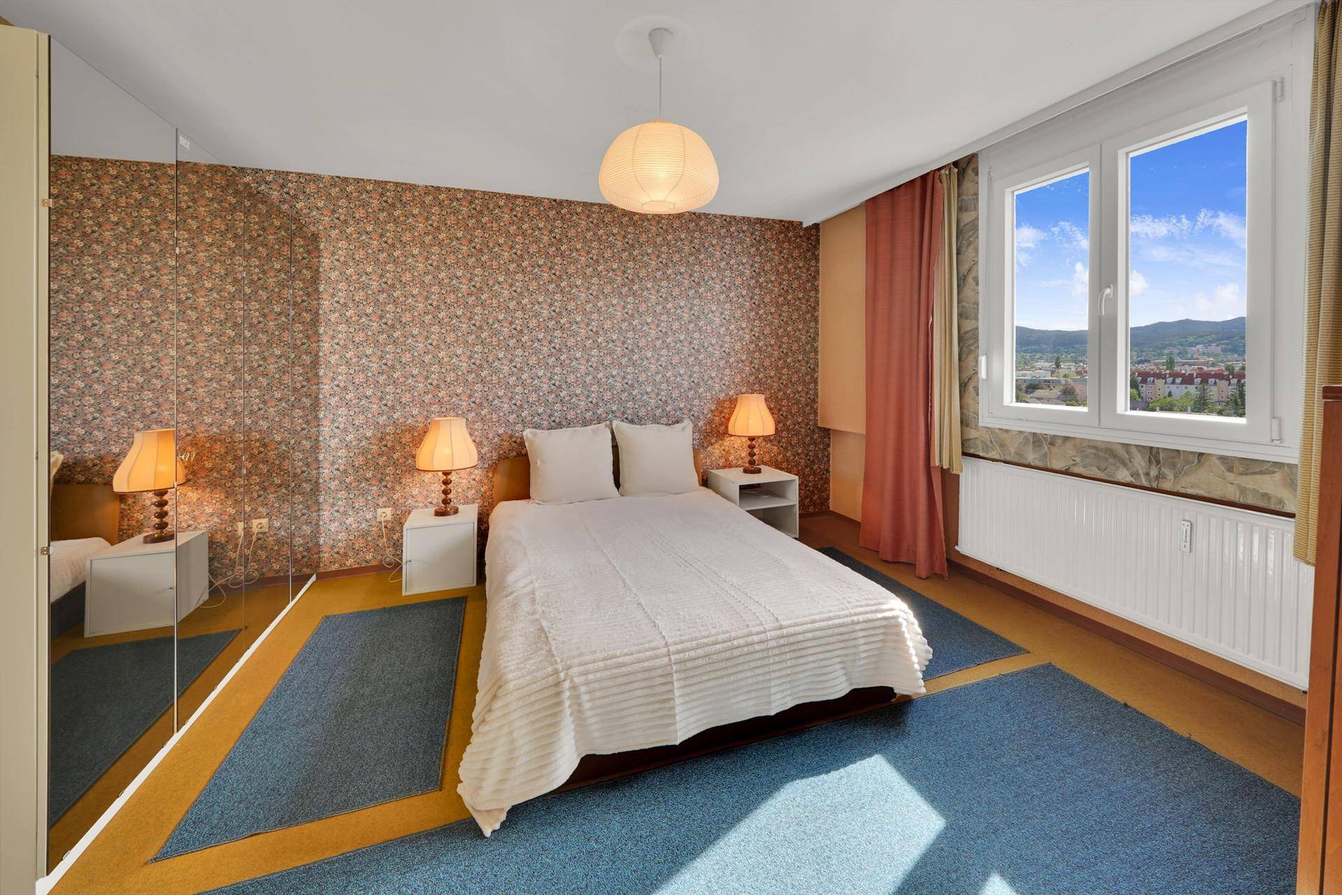 Schlafzimmer mit Doppelbett, Nachttischen und großem Spiegelschrank.