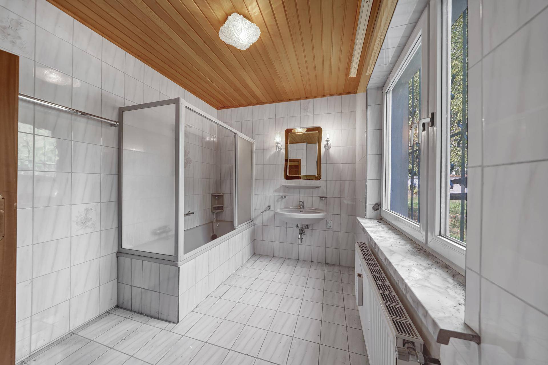 Badezimmer mit Badewanne, Duschabtrennung und Fliesen an Wänden und Boden.
