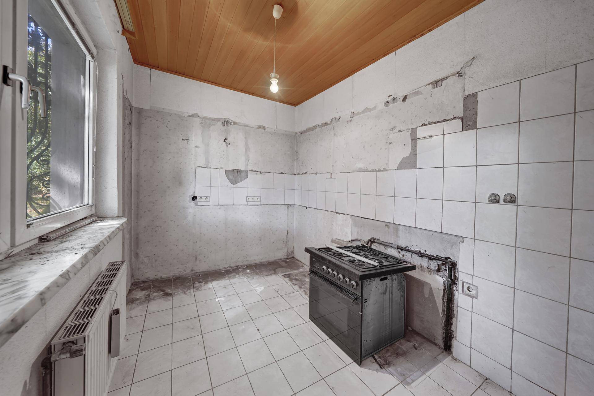 Unfertige Küche mit Fliesenboden und Gasherd, bereit für eine Modernisierung.