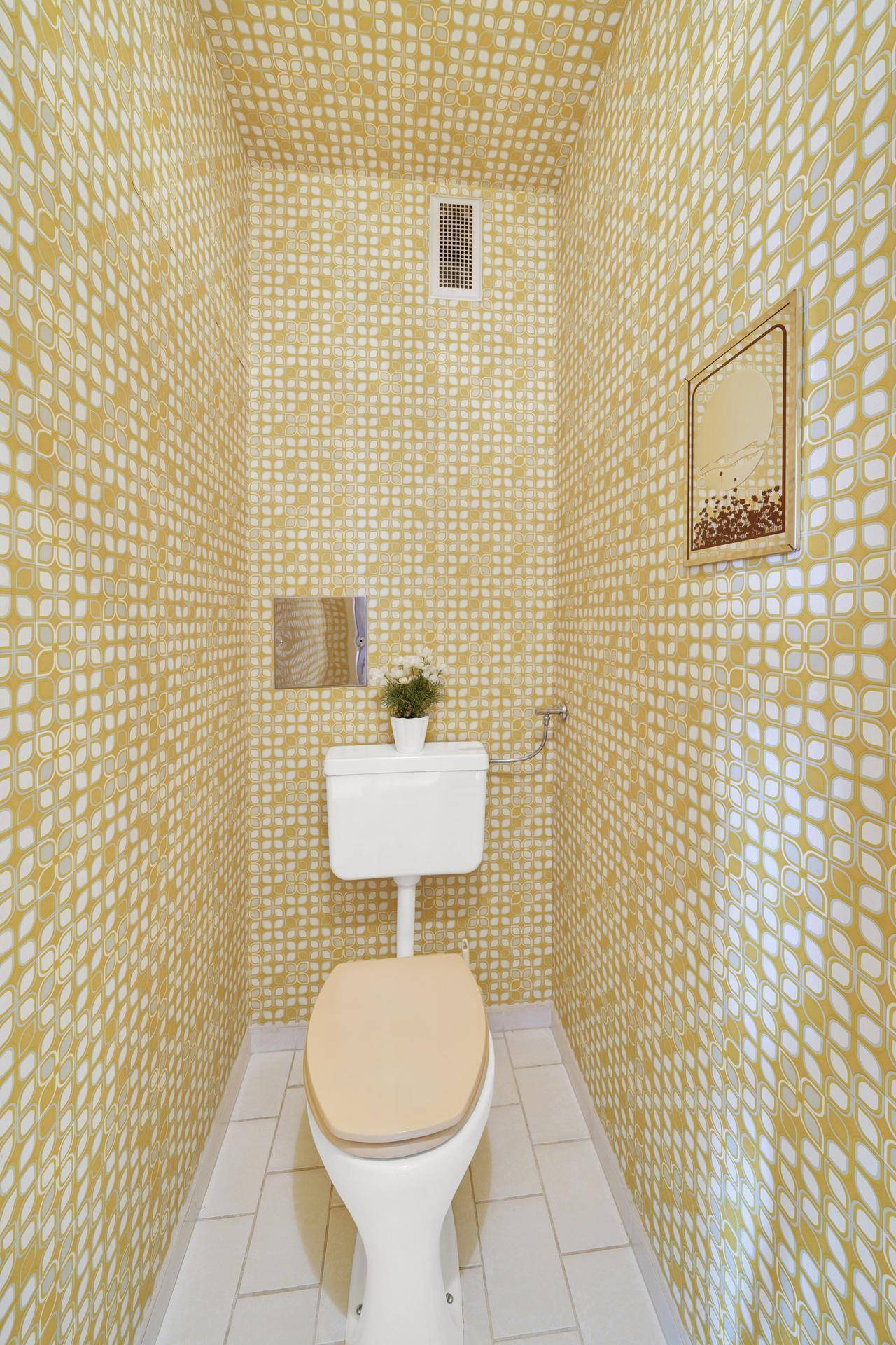 Kleines Gäste-WC mit auffälliger Tapete und einfacher Toilette.