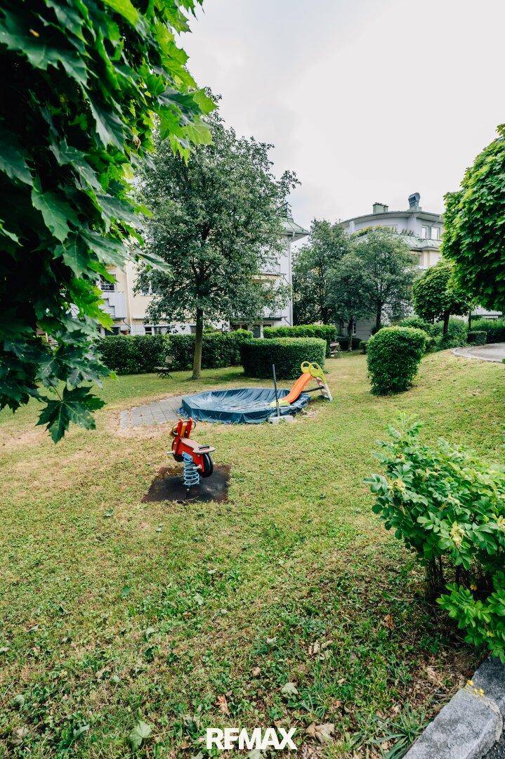 Gemeinschaftlicher Gartenbereich mit kleinem Planschbecken, Rutsche und Federwippe für Kinder.