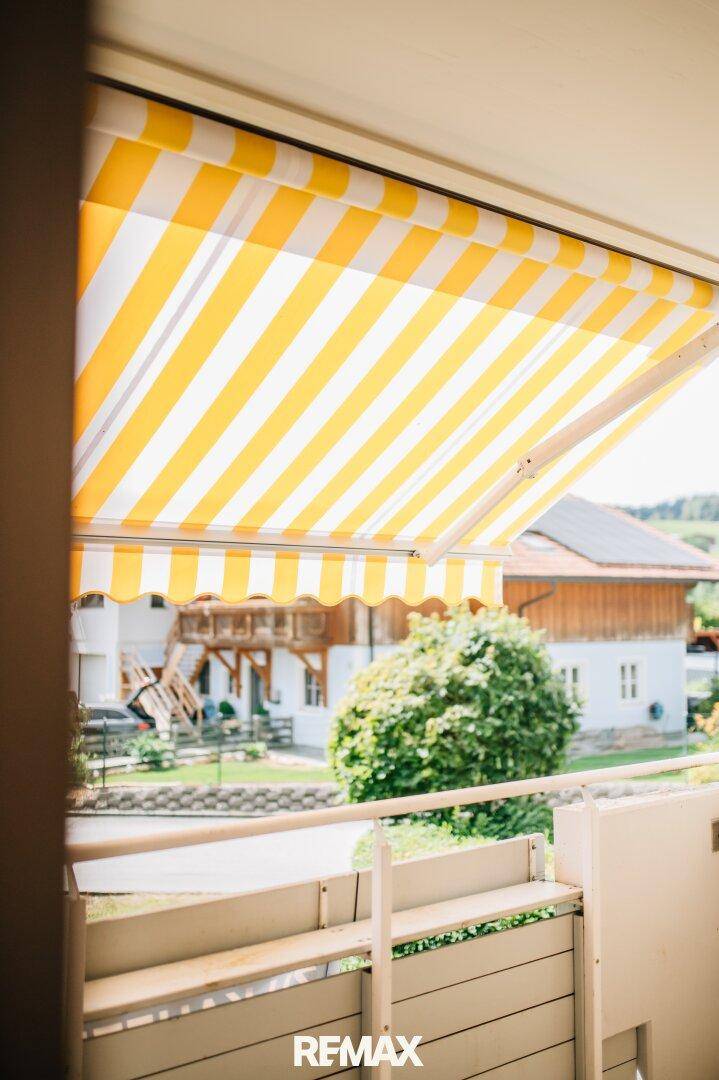 Nahaufnahme einer gelb-weiß gestreiften Markise auf dem Balkon, die Schatten spendet.