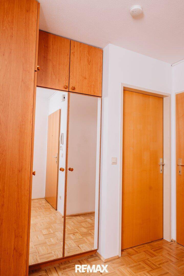 Flur mit Parkettboden, Holztüren und einem Einbauschrank mit Spiegelfronten.