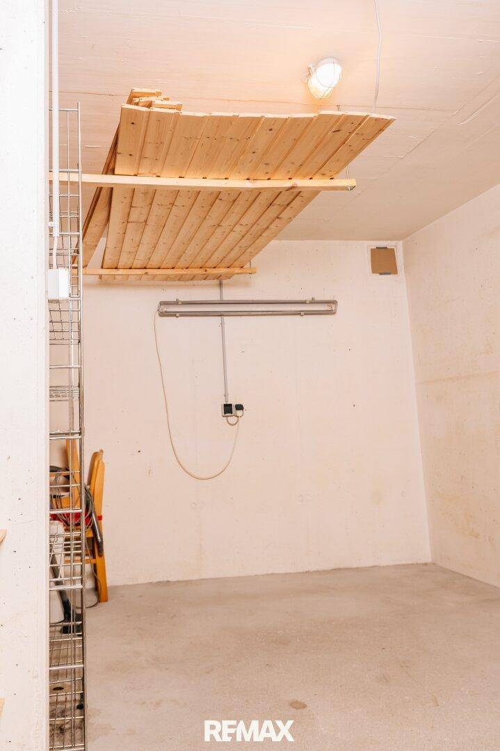 Einfacher Abstellraum im Keller mit Betonboden und Holzbrettern an der Decke.