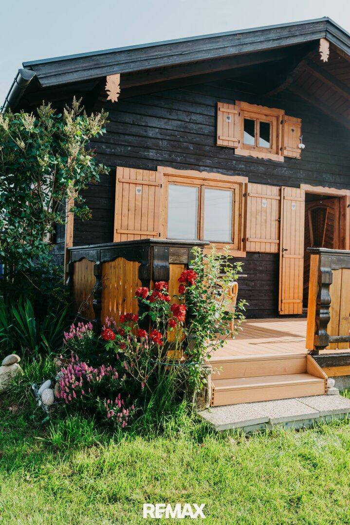 Idyllisches Holzchalet umgeben von blühenden Blumen und grüner Wiese.