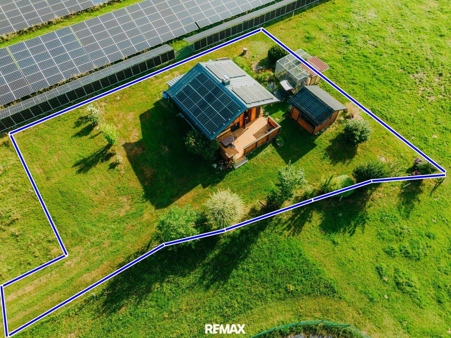 Luftaufnahme des Grundstücks mit blau eingezeichneten Grenzen und Solaranlage.