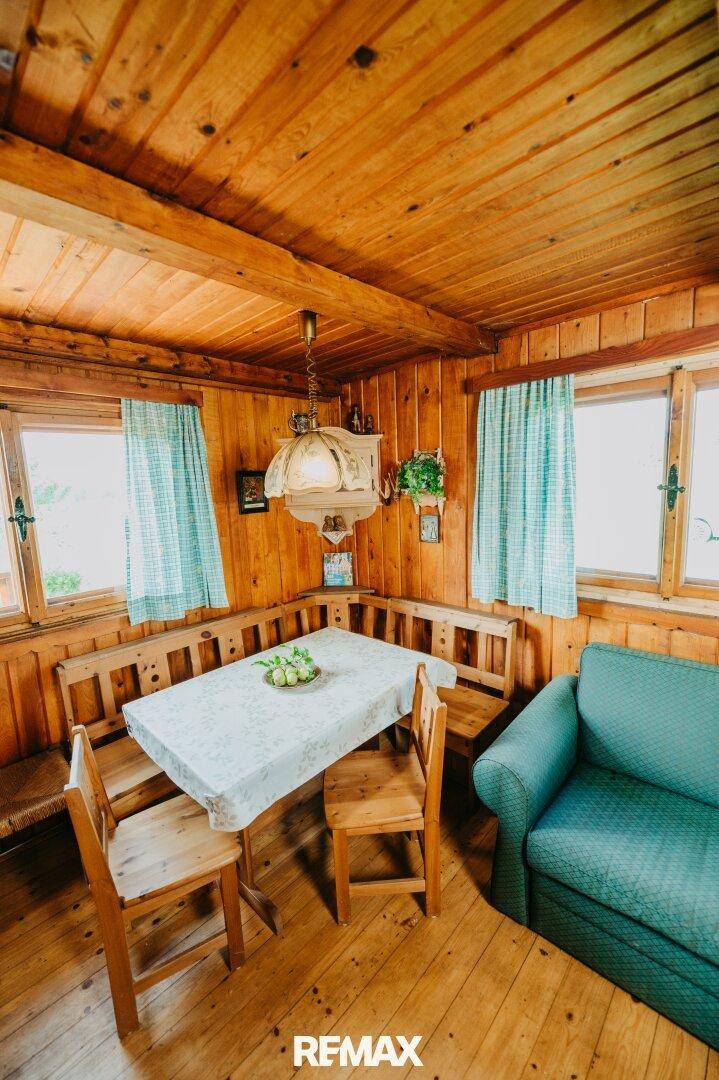 Gemütlicher Wohn-Essbereich mit Holzbänken, Esstisch und Sofa.