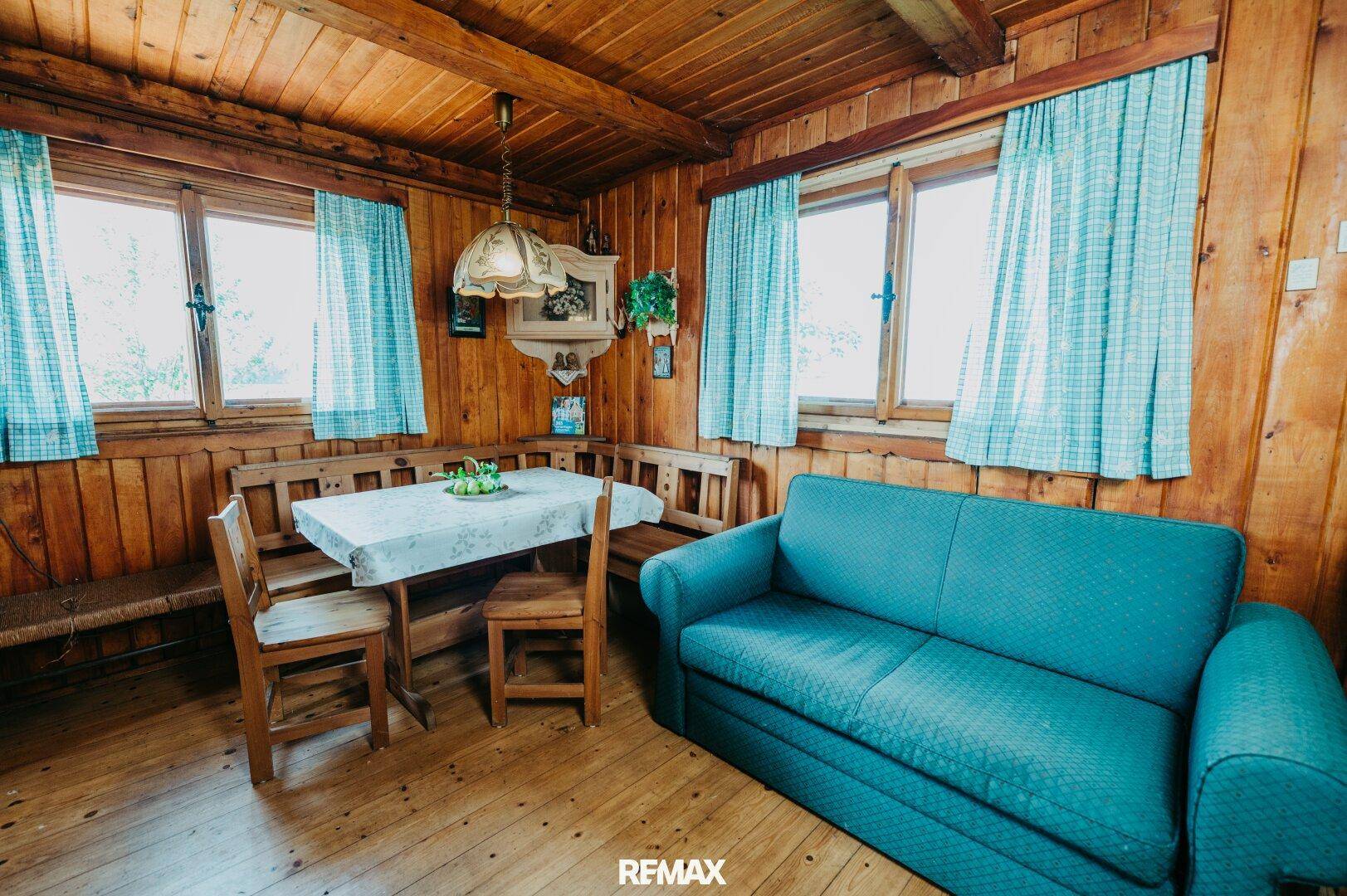 Heller Wohn-Essbereich mit Holzbänken, Esstisch und Sofa in traditionellem Stil.
