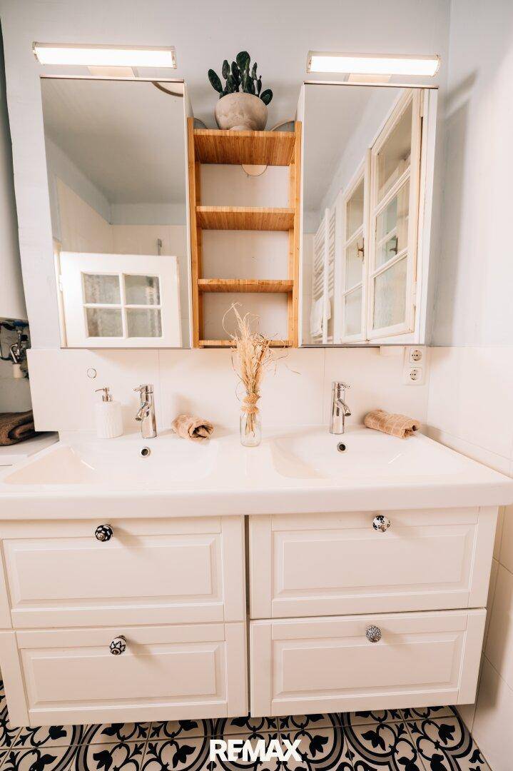 Modernes Badezimmer mit Doppelwaschbecken, Spiegelschränken und gemusterten Fliesen.