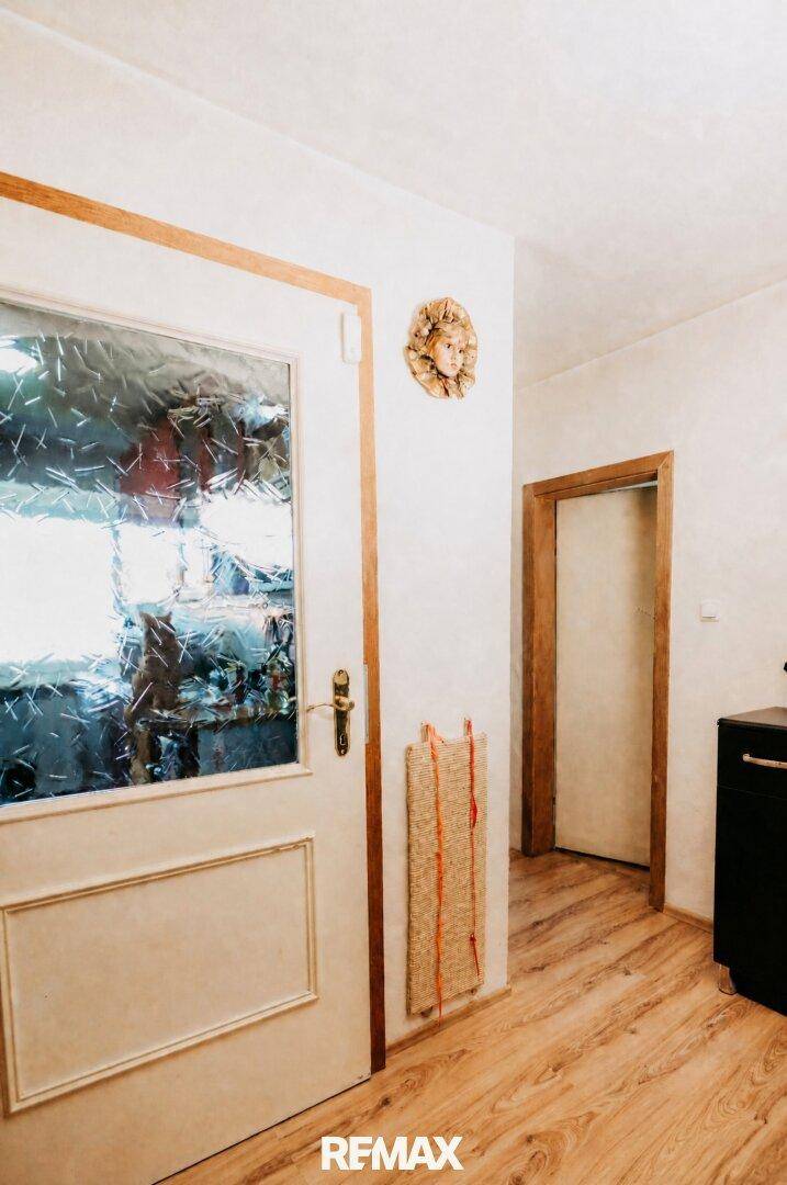 Flur mit Holzboden und einer Tür mit Glaseinsatz, die zu einem weiteren Raum führt.