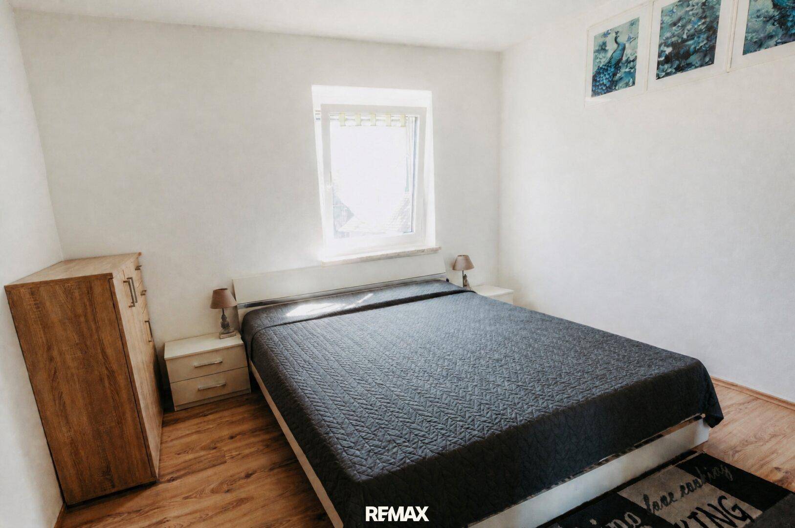 Schlafzimmer mit Doppelbett, Nachttischen und Laminatboden, in einem hellen Ambiente.