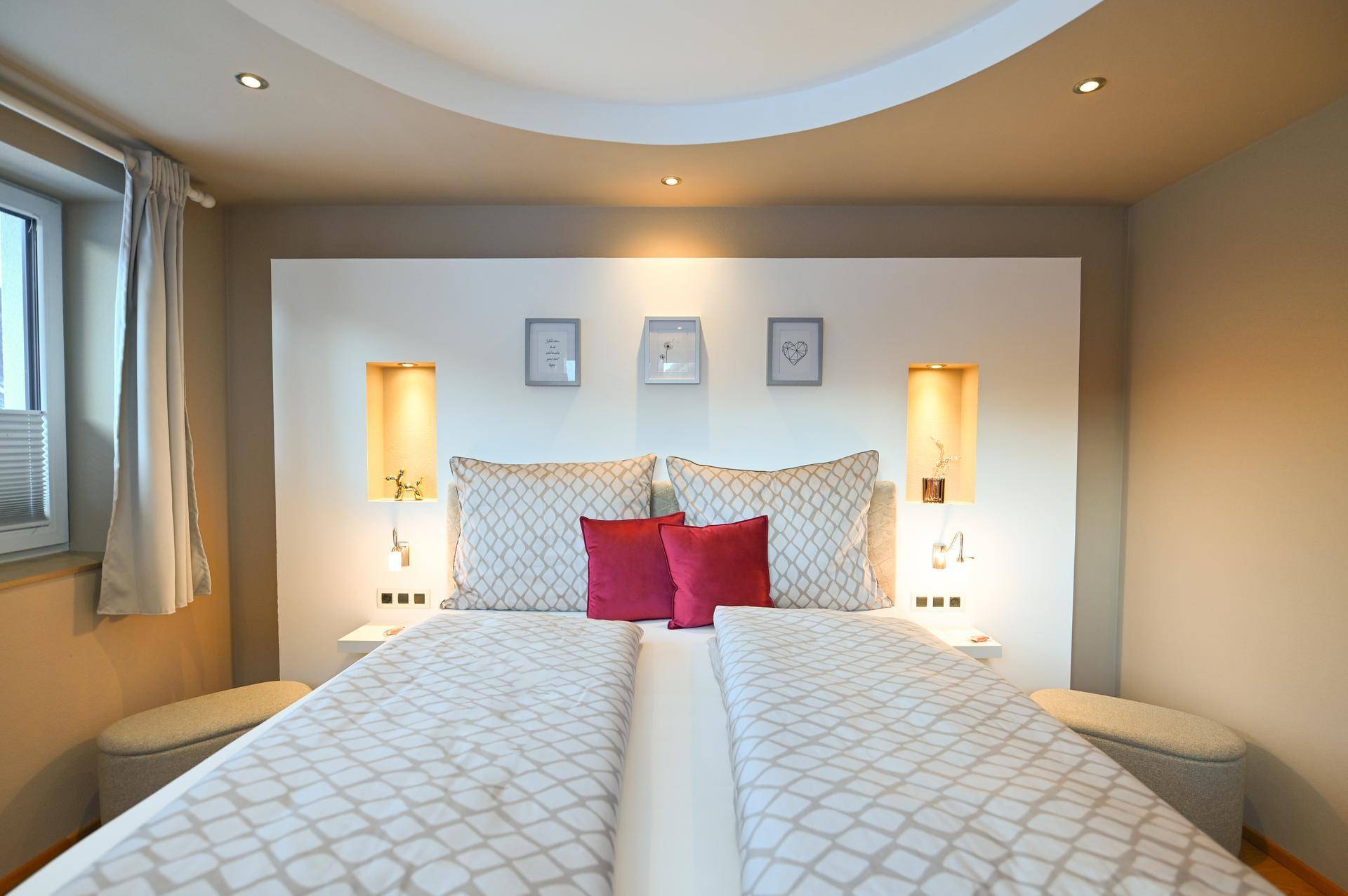 Modernes Schlafzimmer mit Doppelbett und stilvollem Kopfteil mit integrierter Beleuchtung.