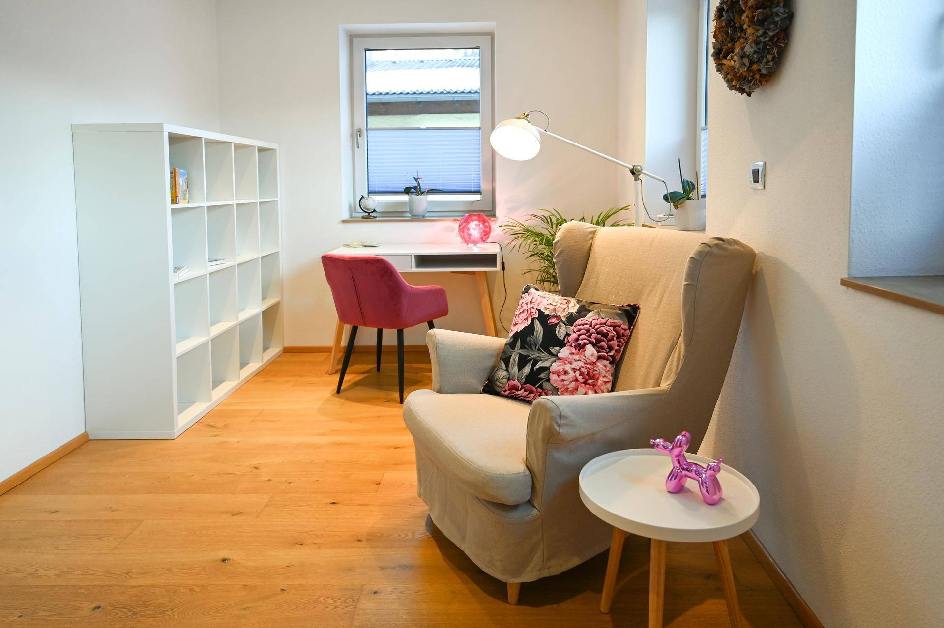 Helles Arbeitszimmer mit Schreibtisch, bequemen Sessel und Bücherregal, ideal für Home-Office.